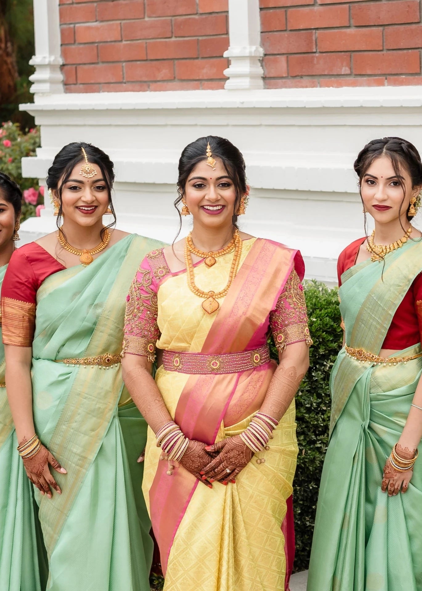 Bride Shivani posing with bridesmaids in a pink silk blouse & belt, intricately handcrafted with beads, stones, resham, sequins and zardozi by team Archana Karthick.