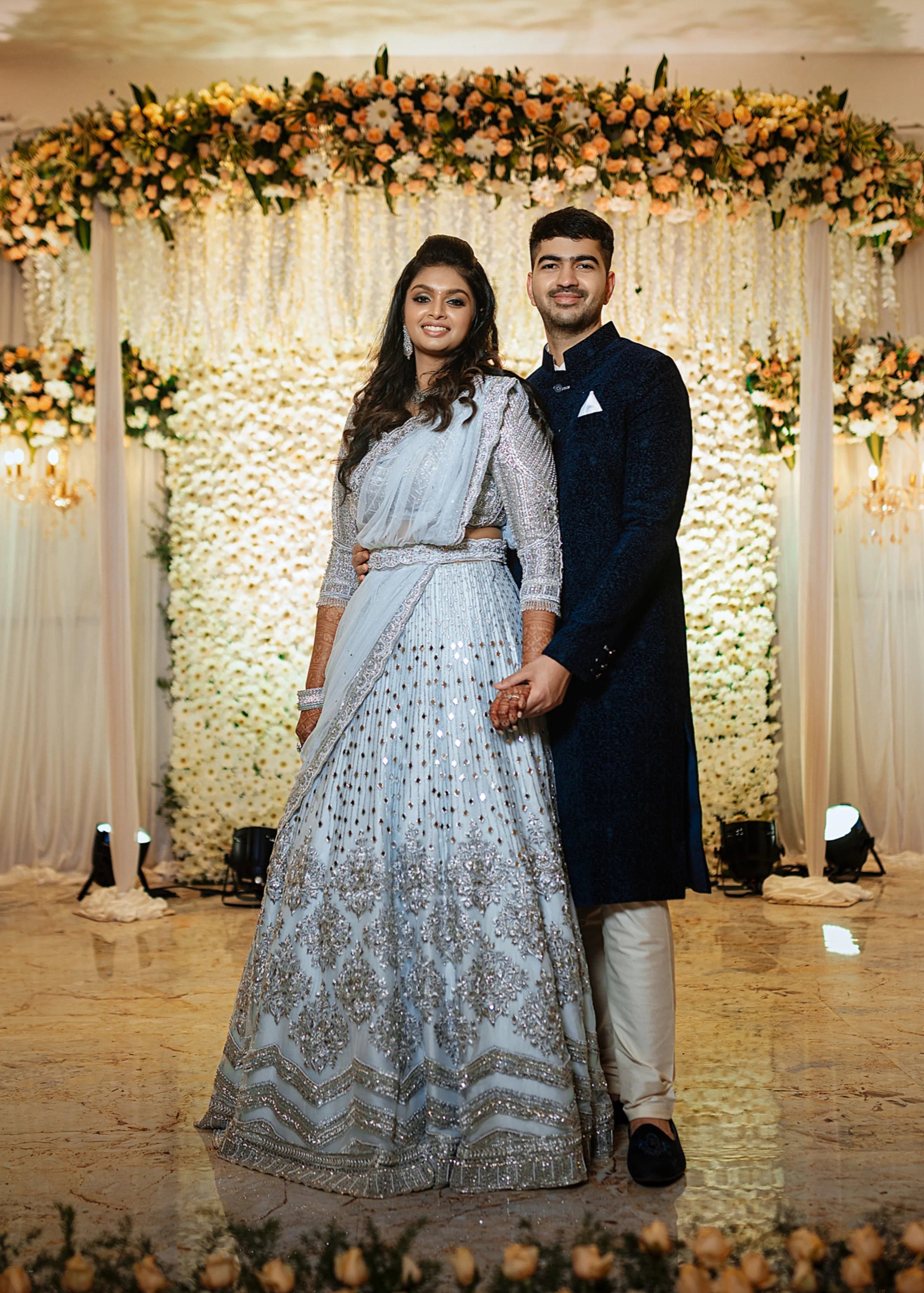Bride Shreya from USA posing with groom in a handcrafted powder blue net lehenga embellished with mirrors, pearls, zardozi, and crystals.