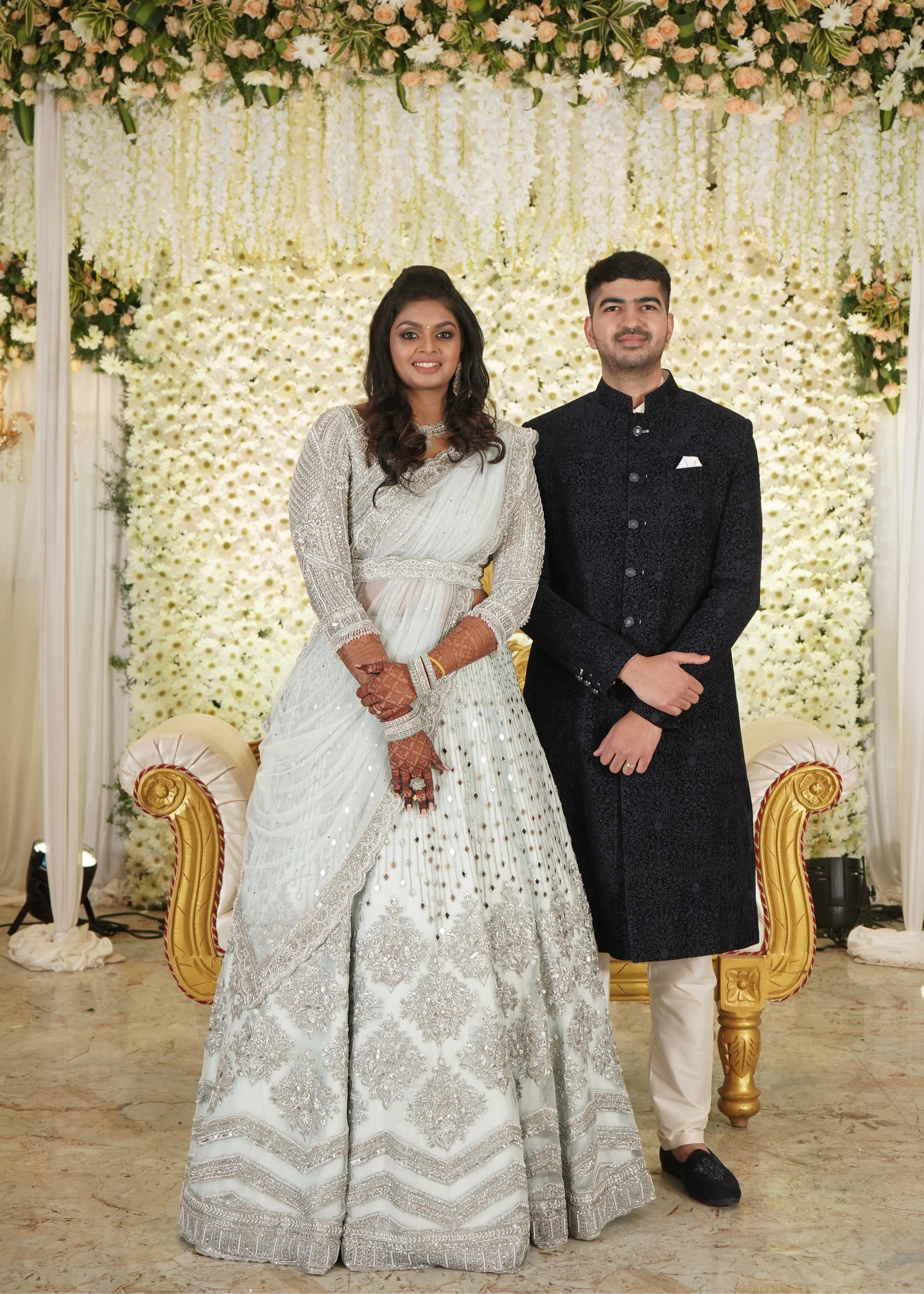 Bride Shreya from USA posing with her groom in a handcrafted powder blue net lehenga embellished with mirrors, pearls, zardozi, and crystals.