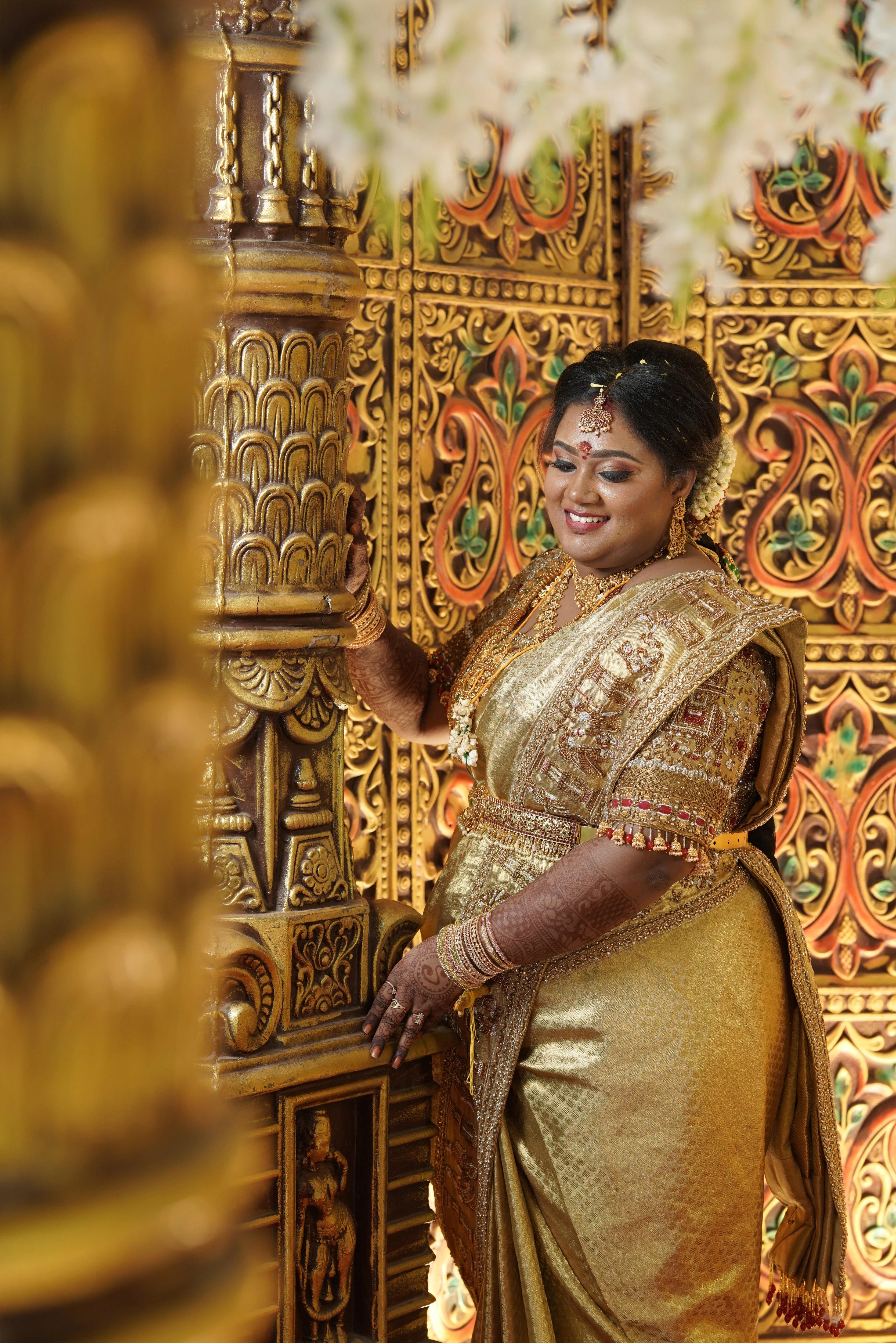 Bride Shyamaladevi posing in a gold palanquin concept silk blouse & saree border, intricately handcrafted with coins, jhumkas, zardozi etc by team Archana Karthick.