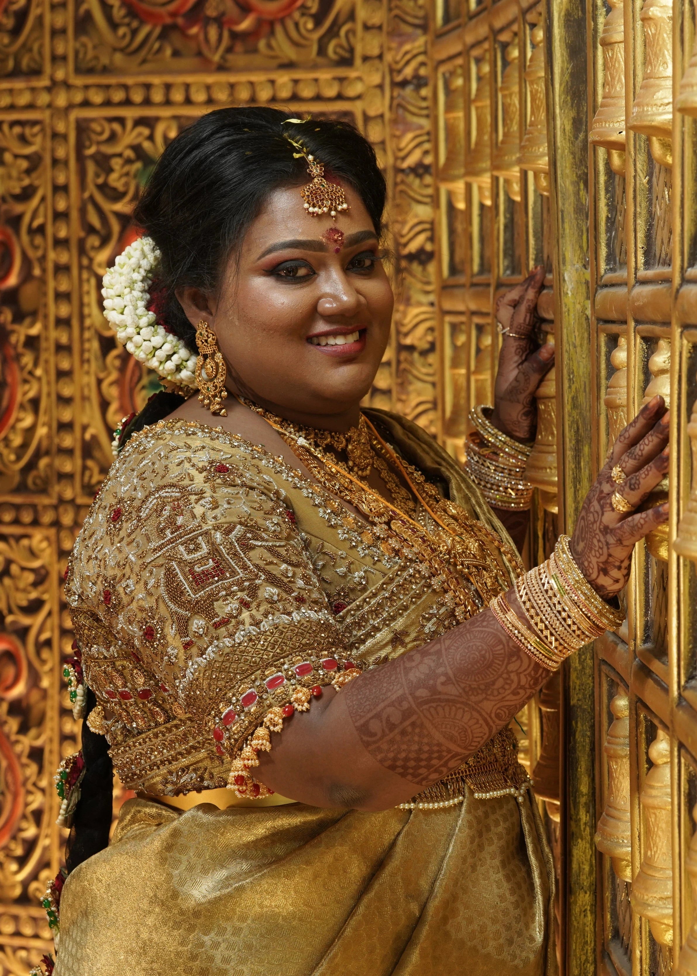 Bride Shyamaladevi smiling in a gold palanquin concept silk blouse & saree border, intricately handcrafted with coins, jhumkas, zardozi etc by team Archana Karthick.