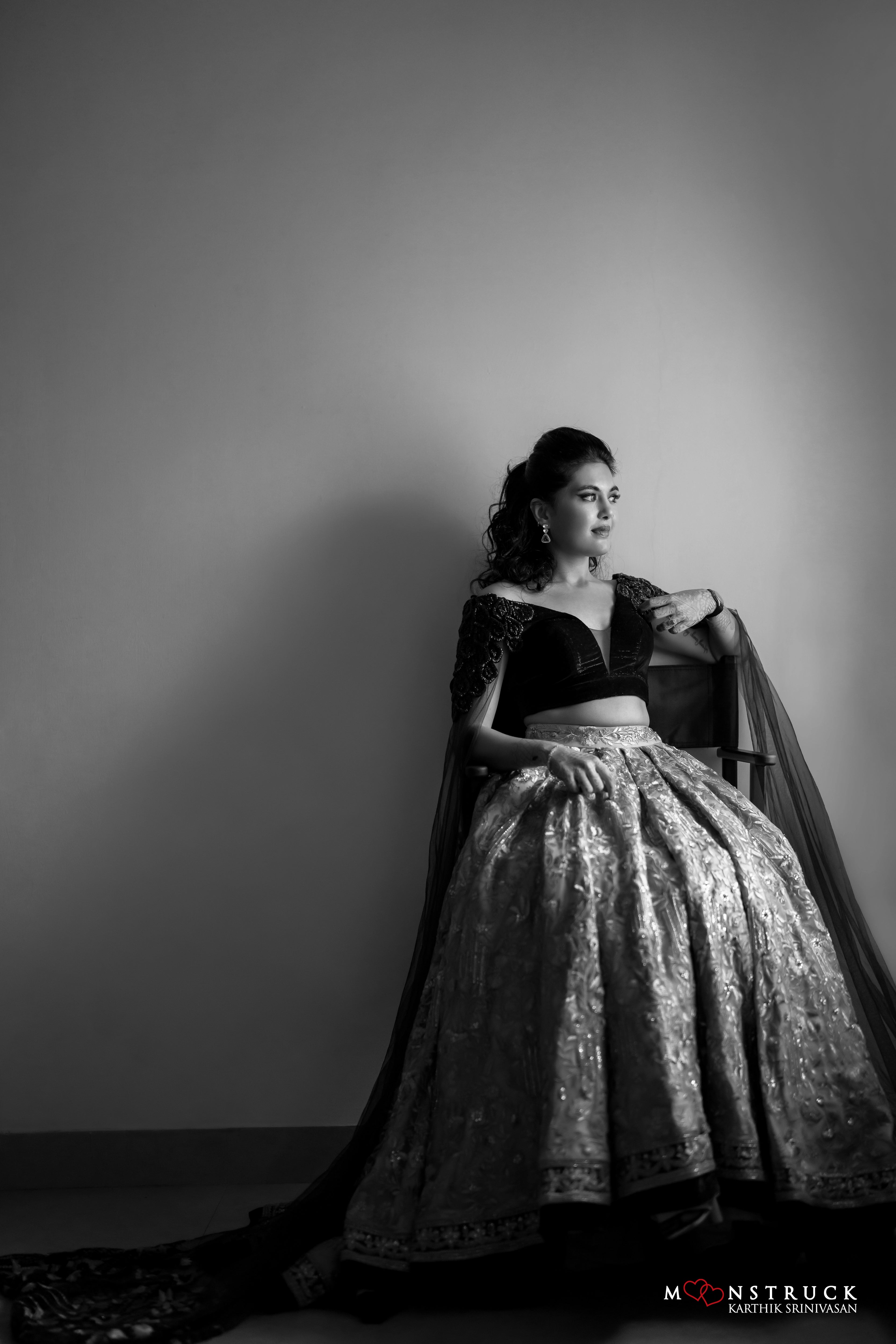 Bride Sneha Murugan seated in a photoshoot in a midnight blue (velvet) and gold (tulle) lehenga, intricately handcrafted with zari, sequins, cutdana and stones by team Archana Karthick.