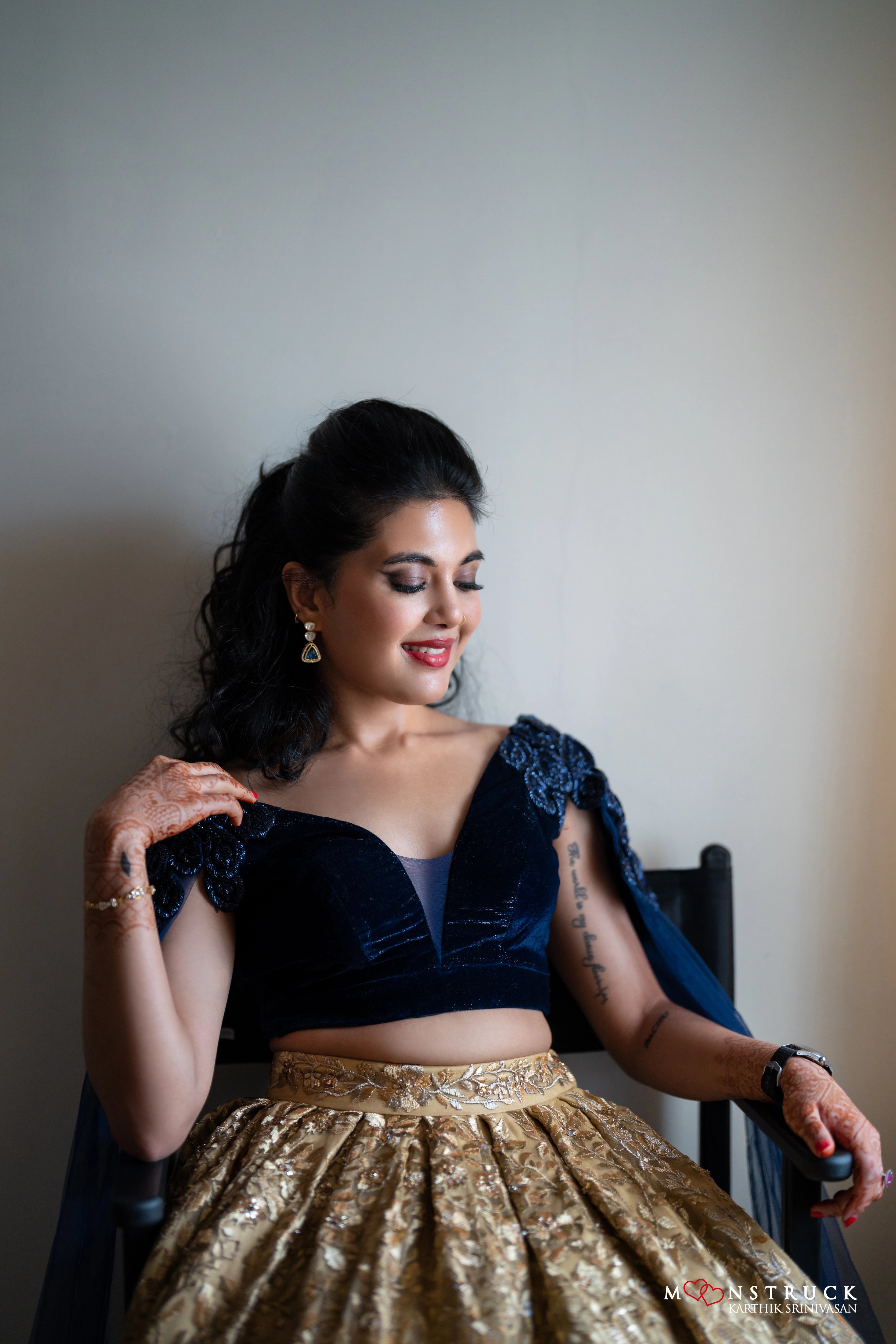 Bride Sneha Murugan smiling in a midnight blue (velvet) and gold (tulle) lehenga, intricately handcrafted with zari, sequins, cutdana and stones by team Archana Karthick.