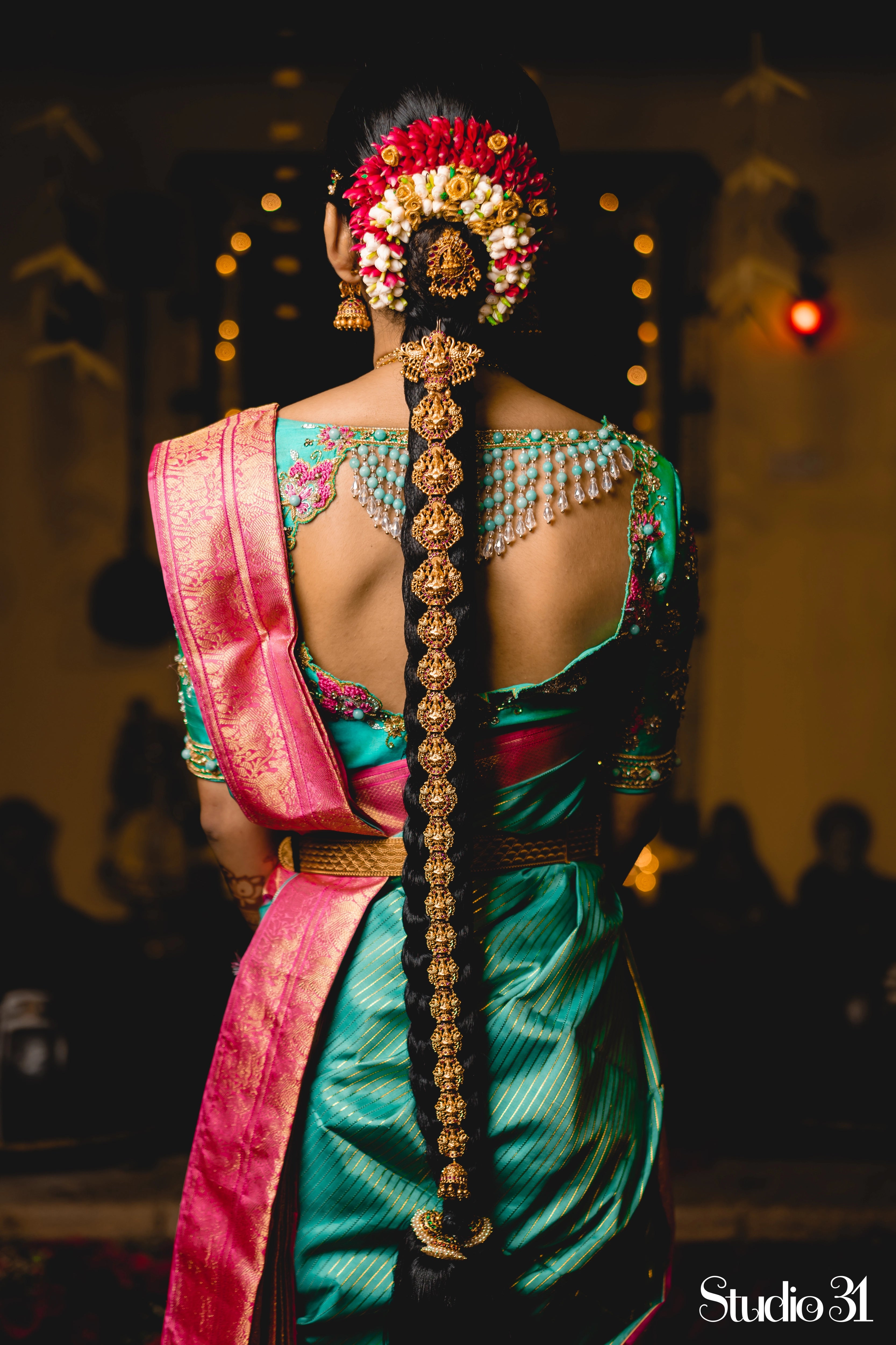 Bride Sruthi Venkatesan from USA, posing for photo in a teal silk blouse by team Archana Karthick.