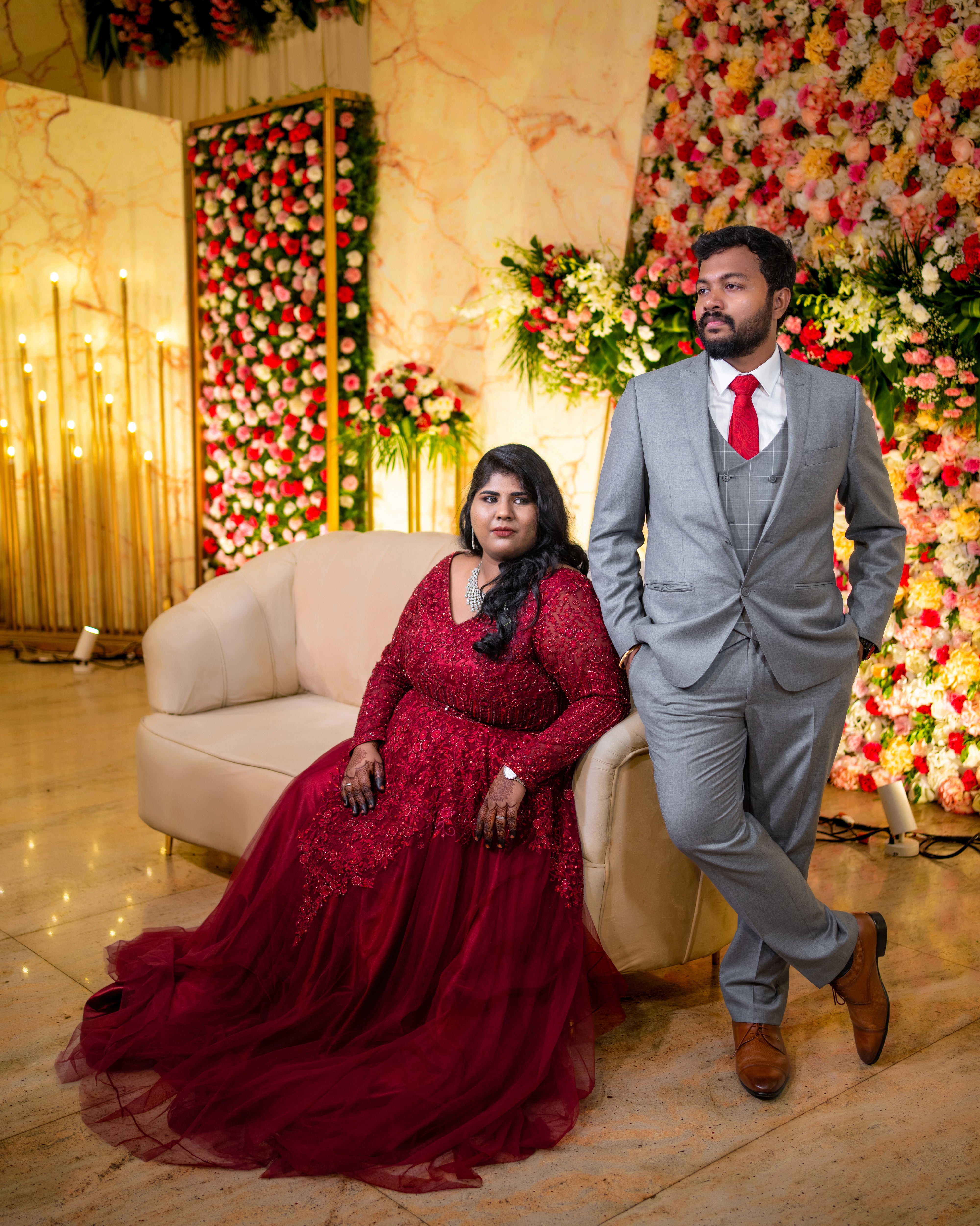 Bride Sushma striking a pose with groom in a red tulle gown, handcrafted intricately with resham, sequins, beads and cutdana by team Archana Karthick.