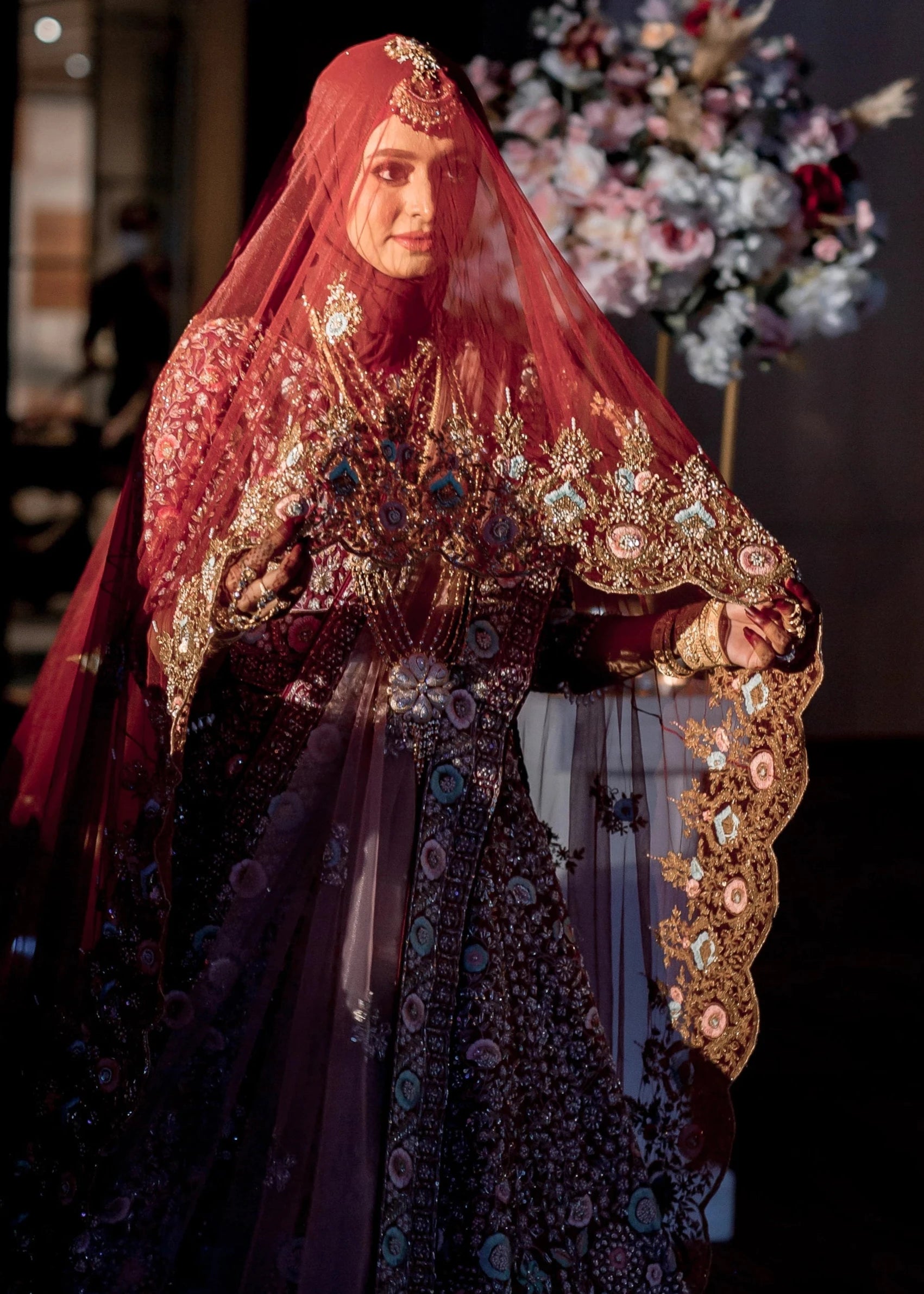 Bride Syaza from Malaysia posing near altar in a maroon tulle veil, intricately handcrafted with zardozi, beads, sequins, stones and resham by team Archana Karthick.