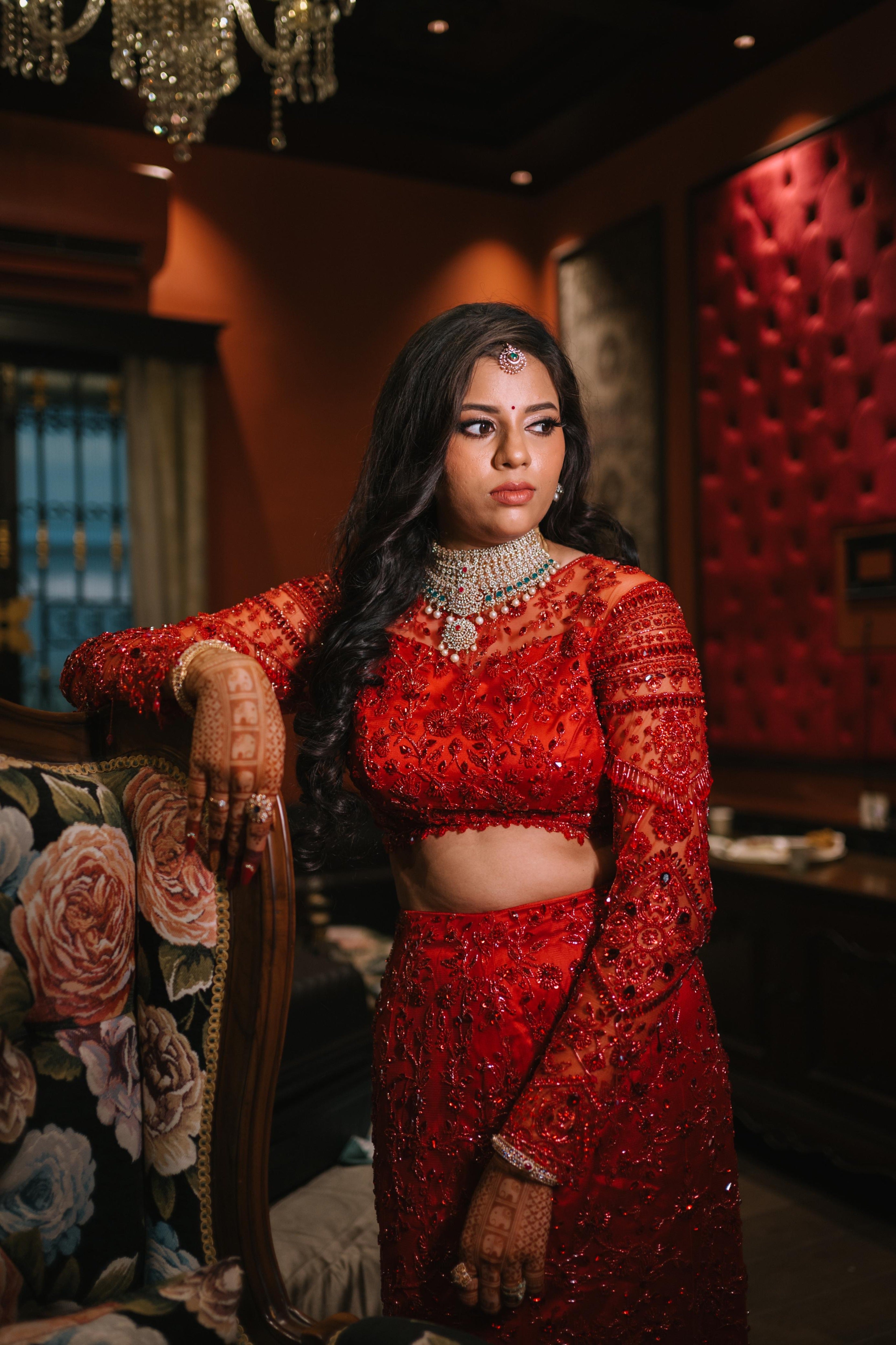 Bride Urmila posing elegantly for her reception in a red handcrafted mermaid lehenga drape designed by Archana Karthick. Full blouse front and sleeve and half of skirt captured.