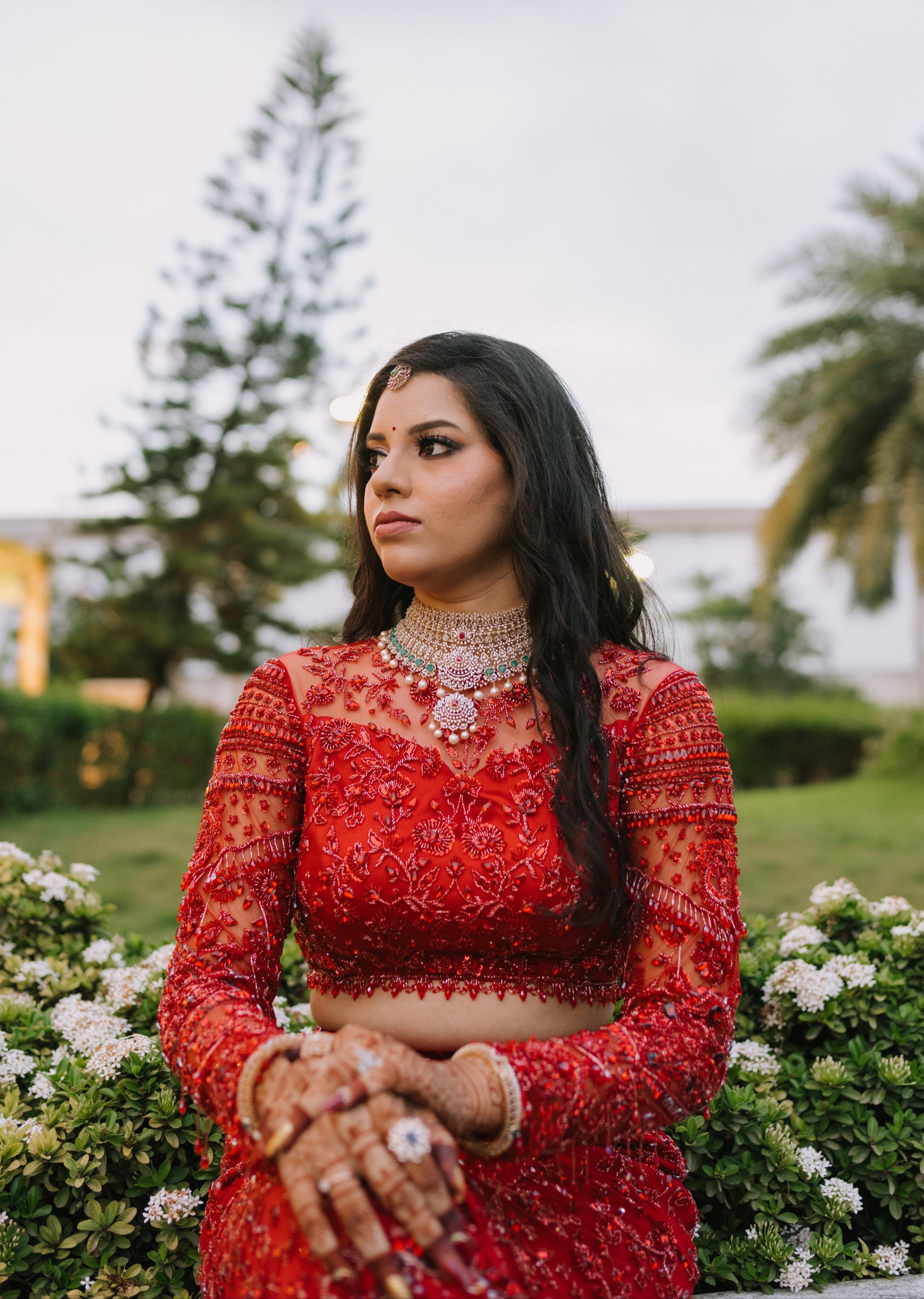 Bride Urmila posing elegantly for her reception in a red handcrafted mermaid lehenga drape designed by Archana Karthick. Full blouse front profile.