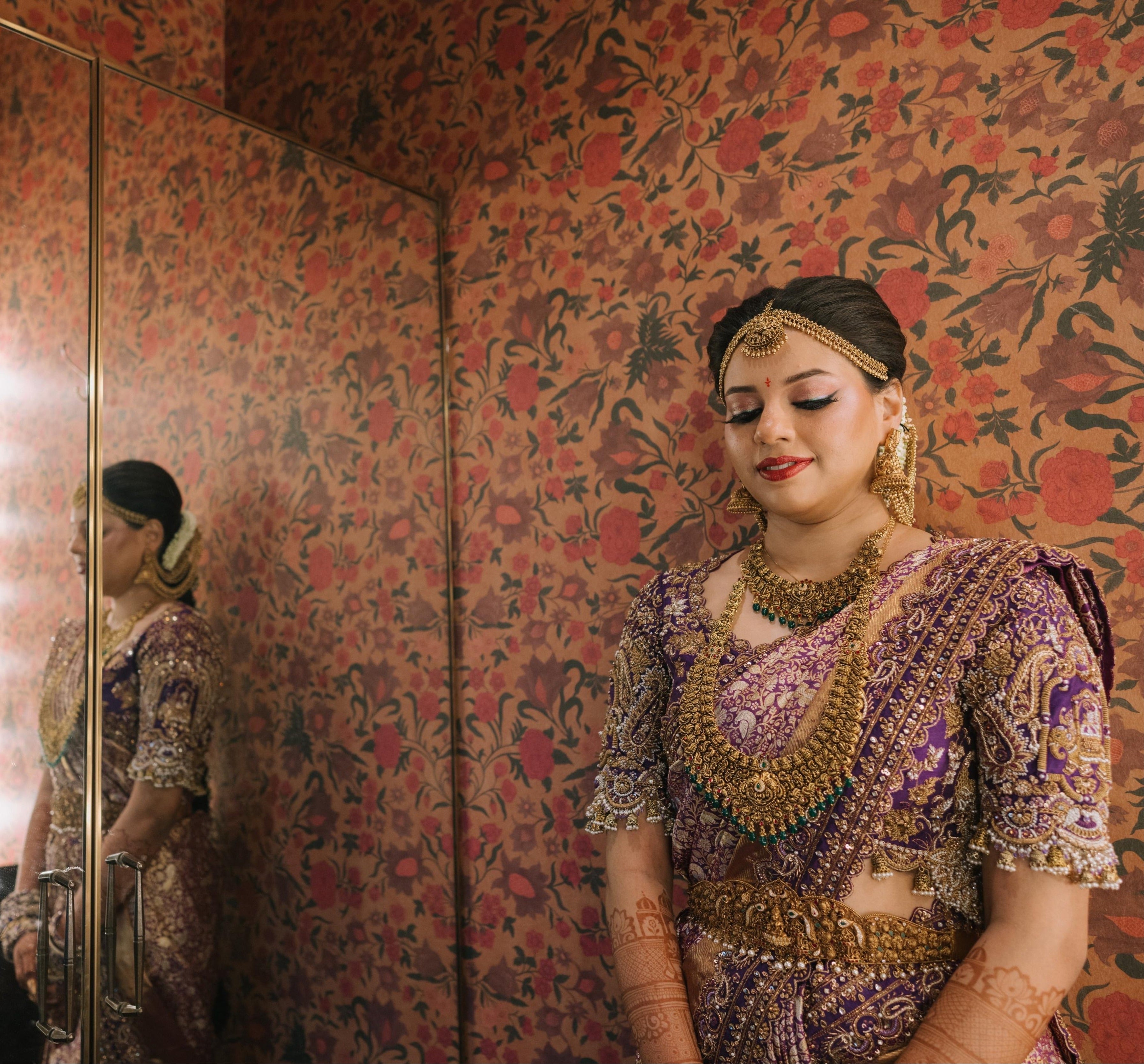 Bride Urmila posing elegantly in a closeup shot of her handcrafted blouse and saree border for her wedding muhurtham designed by Archana Karthick. Posing in makeup room.