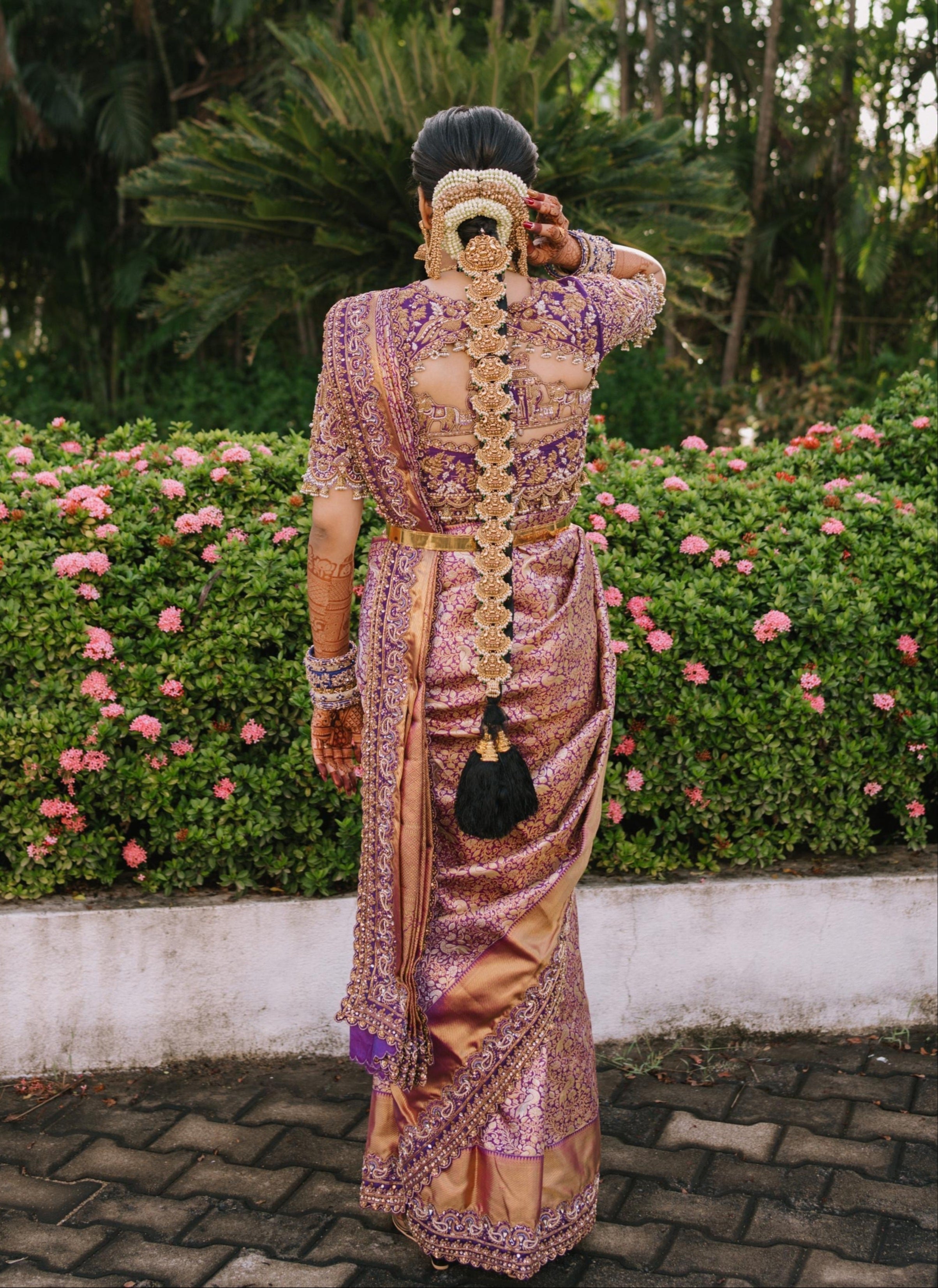 Bride Urmila posing elegantly in a handcrafted blouse and saree border for her wedding muhurtham designed by Archana Karthick. Blouse back design and saree border detailing captured well.