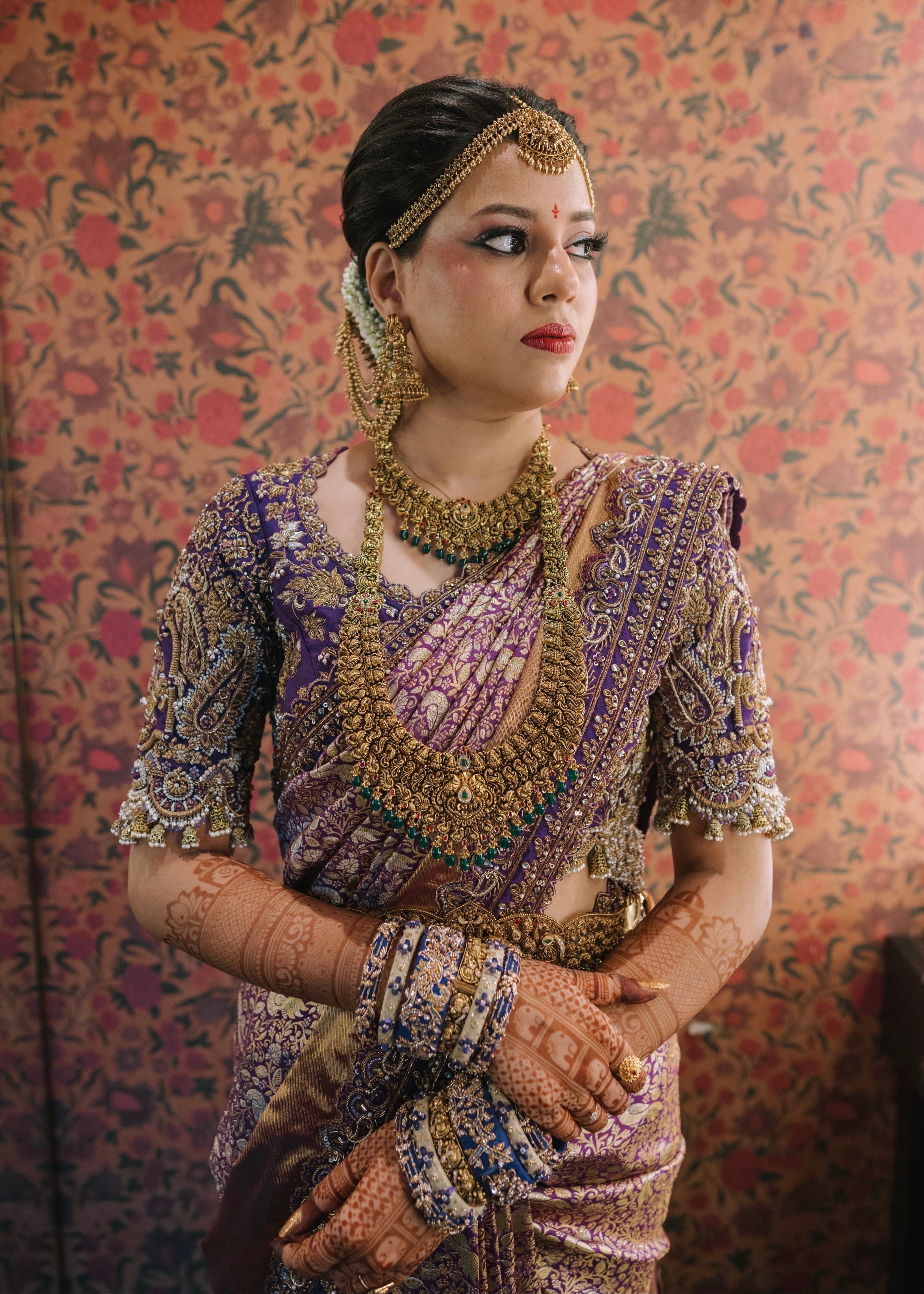 Bride Urmila posing elegantly looking to her left in a handcrafted blouse and saree border for her wedding muhurtham designed by Archana Karthick.