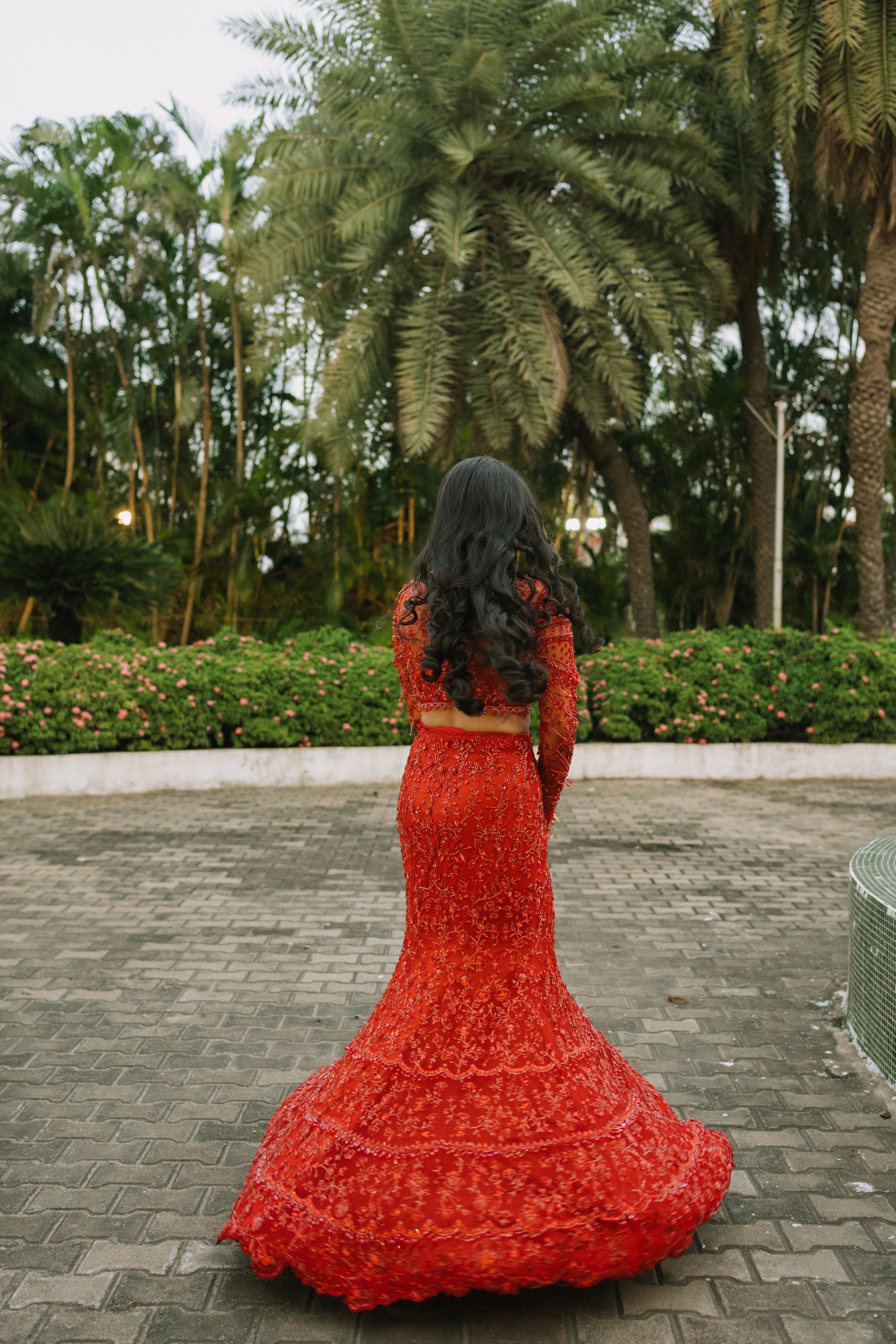 Bride Urmila twirling for her reception in a red handcrafted mermaid lehenga drape designed by Archana Karthick. Back blouse and lehenga design captured.