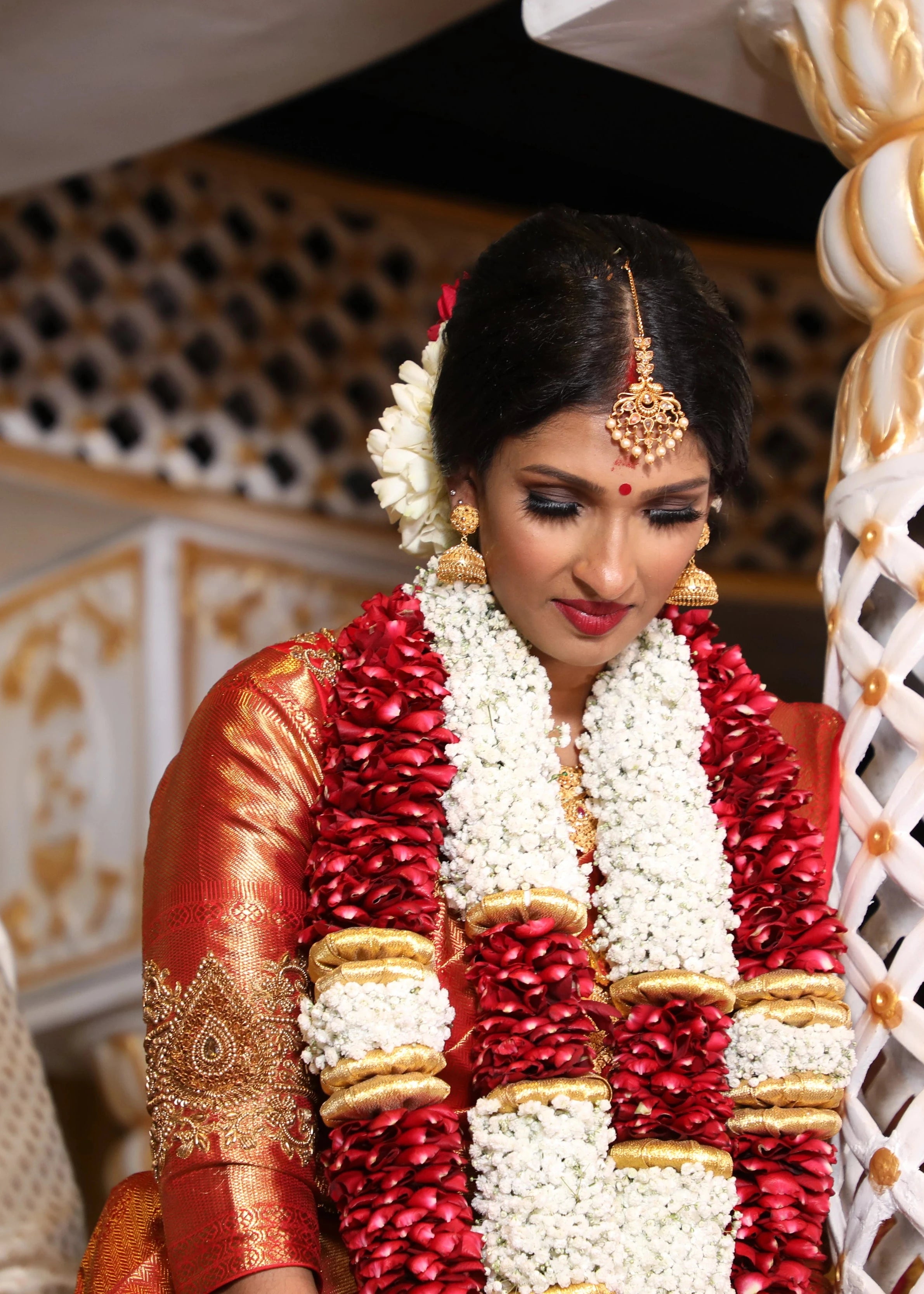 Bride Vithusika from Switzerland looking down in a red silk concept blouse for her wedding, handcrafted with zardozi, beads, sequins and cutdana by team Archana Karthick.