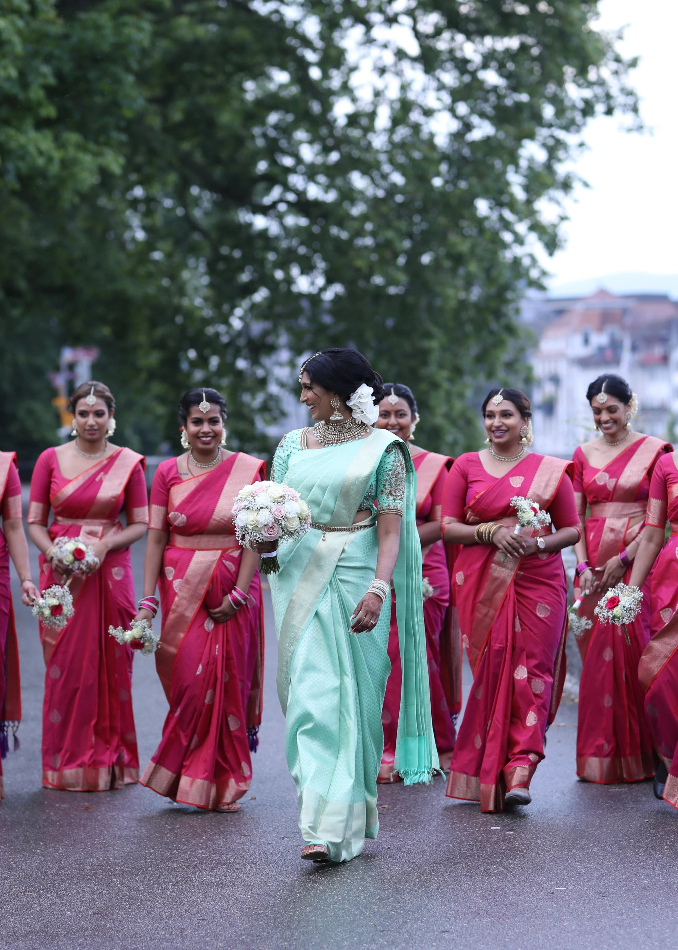 Bride Vithusika from Switzerland walking with bridesmaids in an aquamarine silk concept blouse for her engagement, handcrafted by team Archana Karthick.