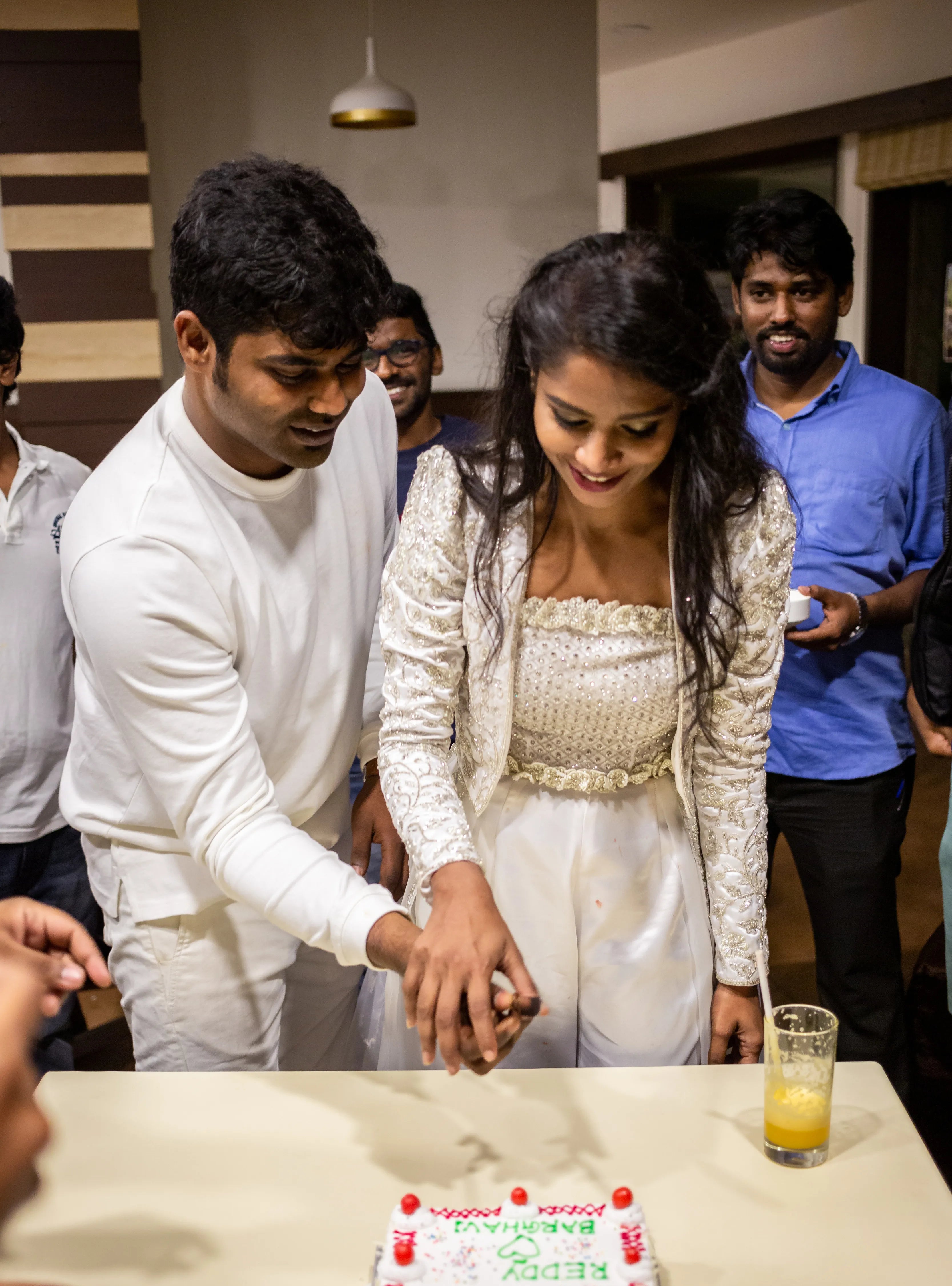 Bride and groom cutting cake in handcrafted silver satin and organza corset outfit embellished with cut dana, pearls, stones and sequins. Designed by Archana Karthick