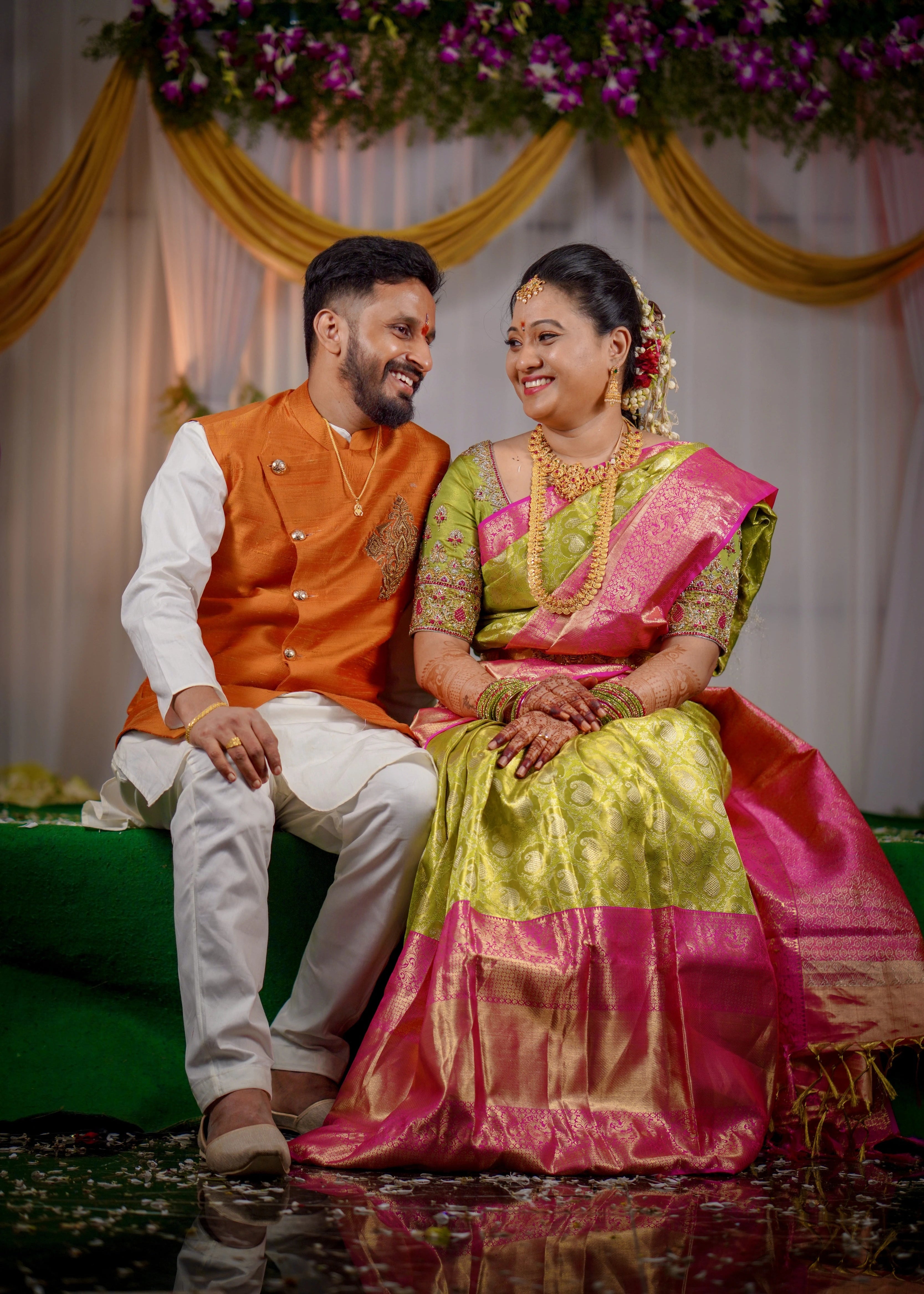 Bride and groom from Seattle, USA posing on stage in a handcrafted blouse and bandhgala set designed by Archana Karthick.