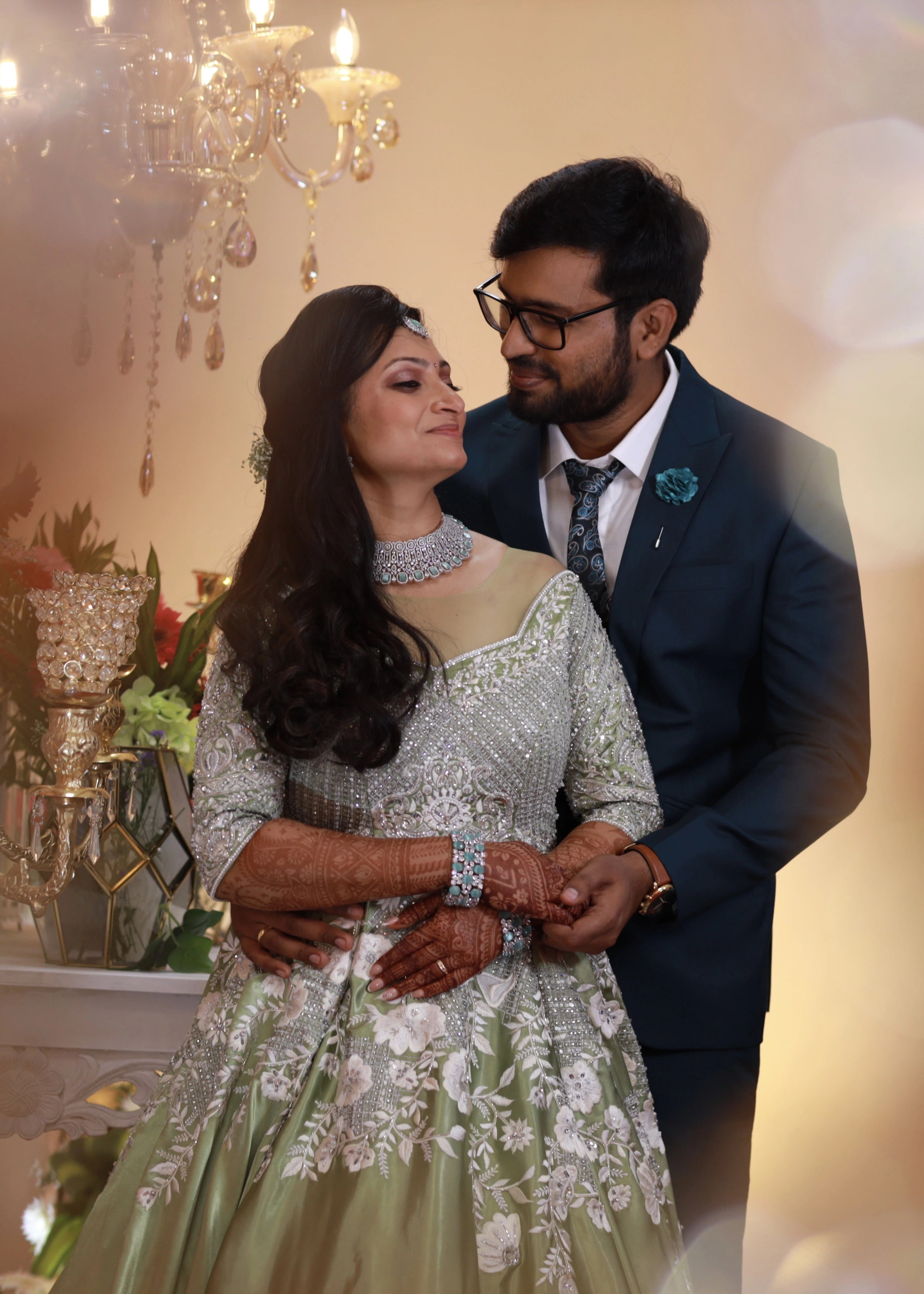 Bride from Canada in an embrace with groom in a handcrafted lime green satin gown with stones, zari, cut dana and sequins work with floral and geometric motifs.