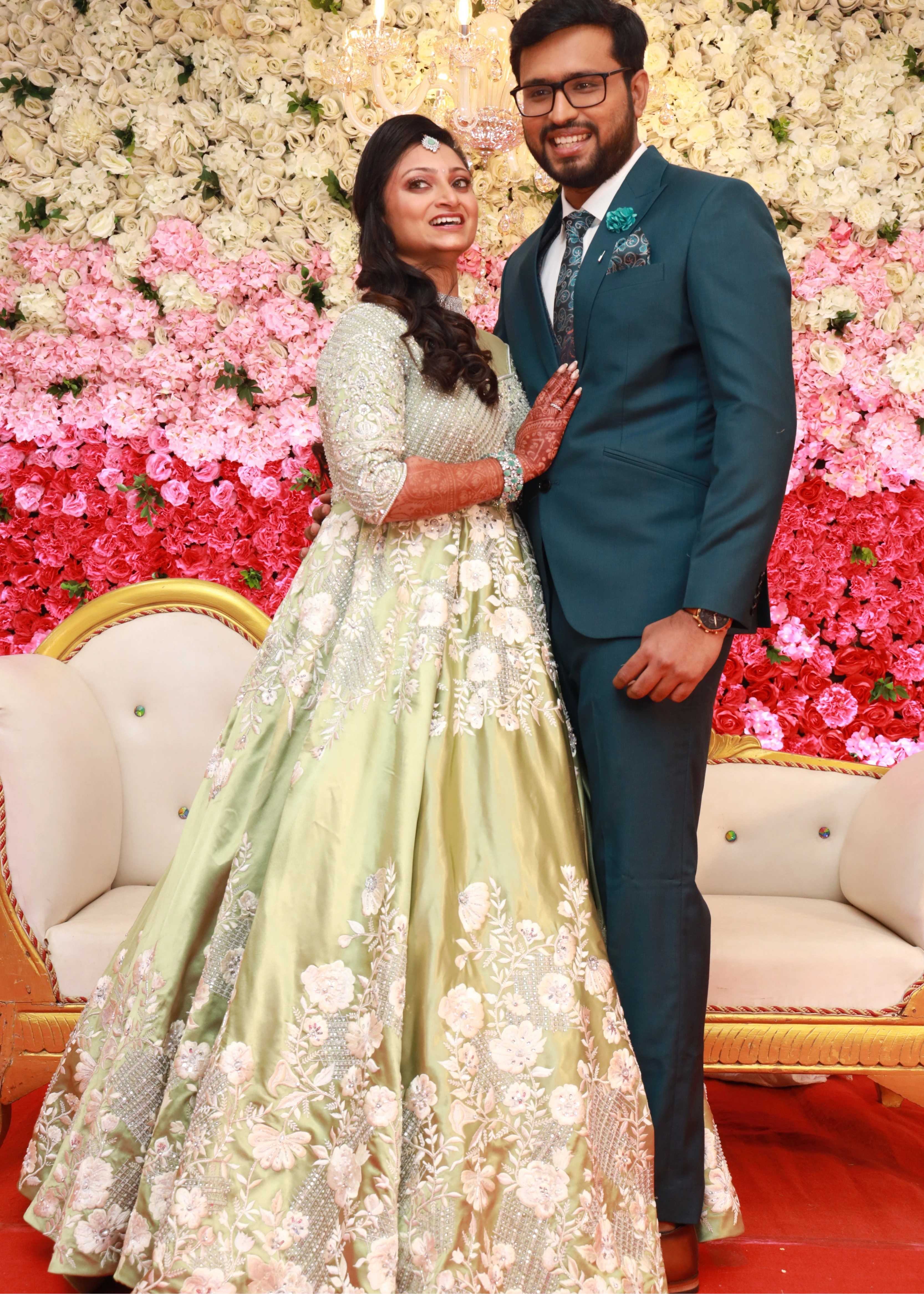Bride from Canada posing with groom in a handcrafted lime green satin gown with stones, zari, cut dana and sequins work with floral and geometric motifs.