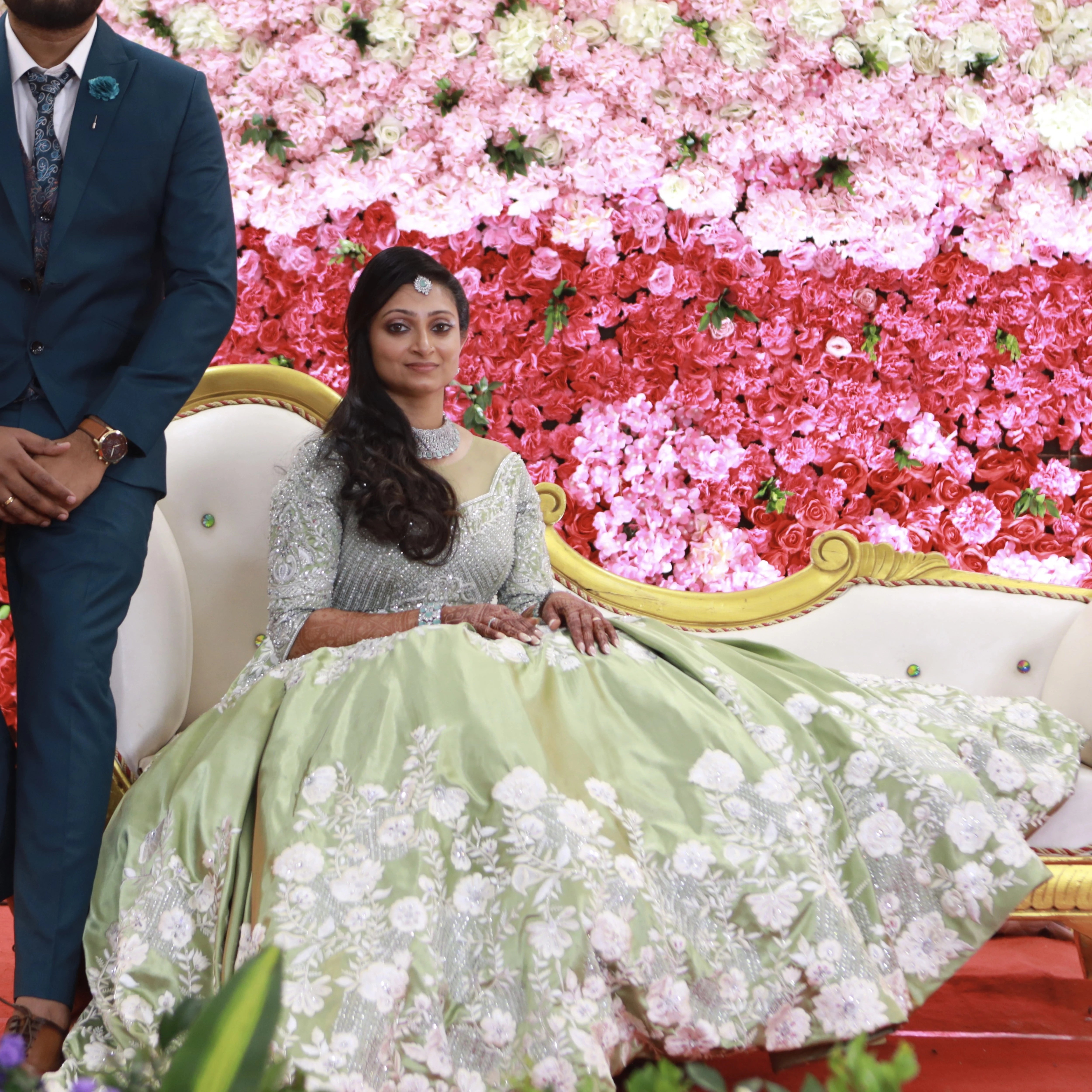Bride from Canada seated with groom in a handcrafted lime green satin gown with stones, zari, cut dana and sequins work with floral and geometric motifs.