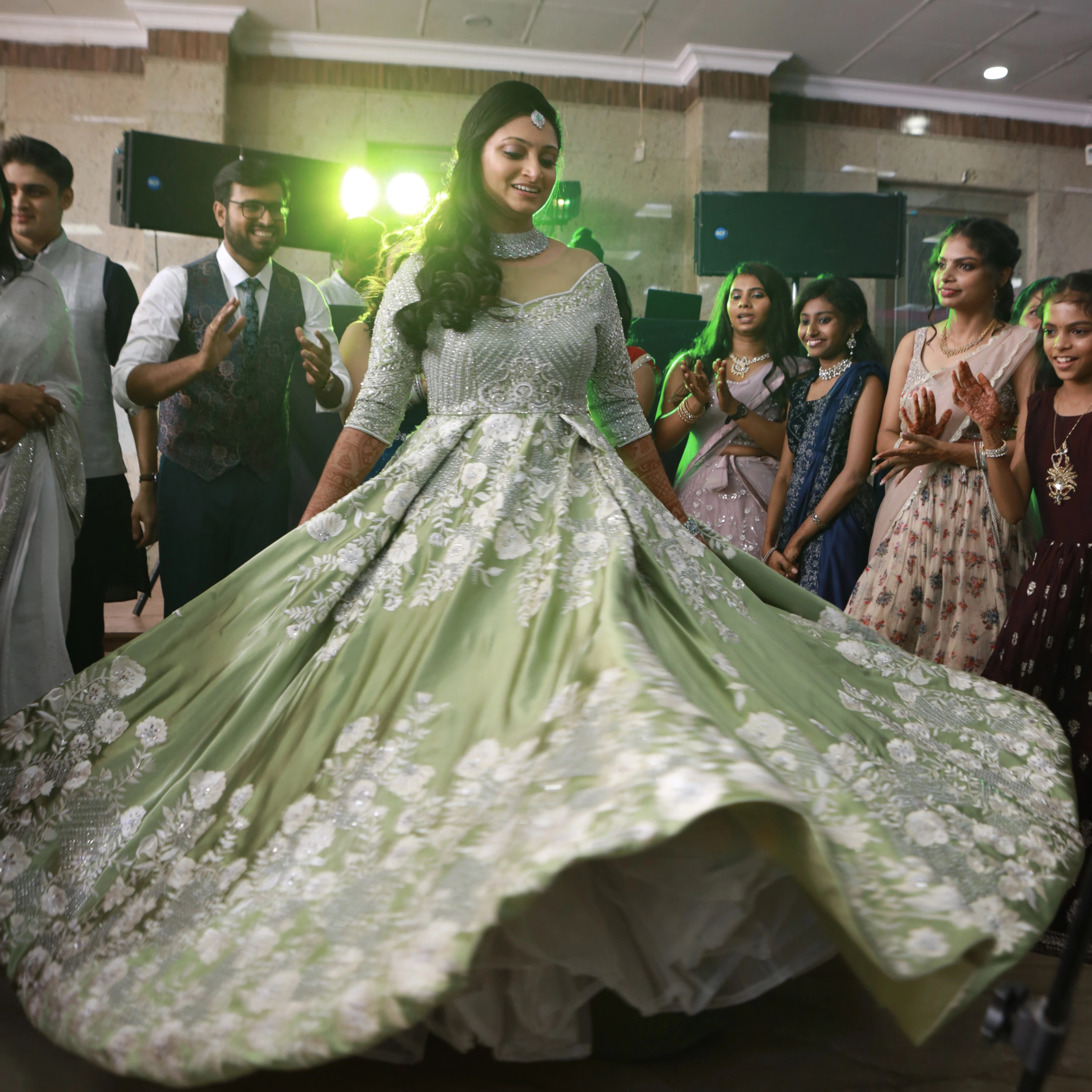 Bride from Canada twirling in a handcrafted lime green satin gown with stones, zari, cut dana and sequins work with floral and geometric motifs.