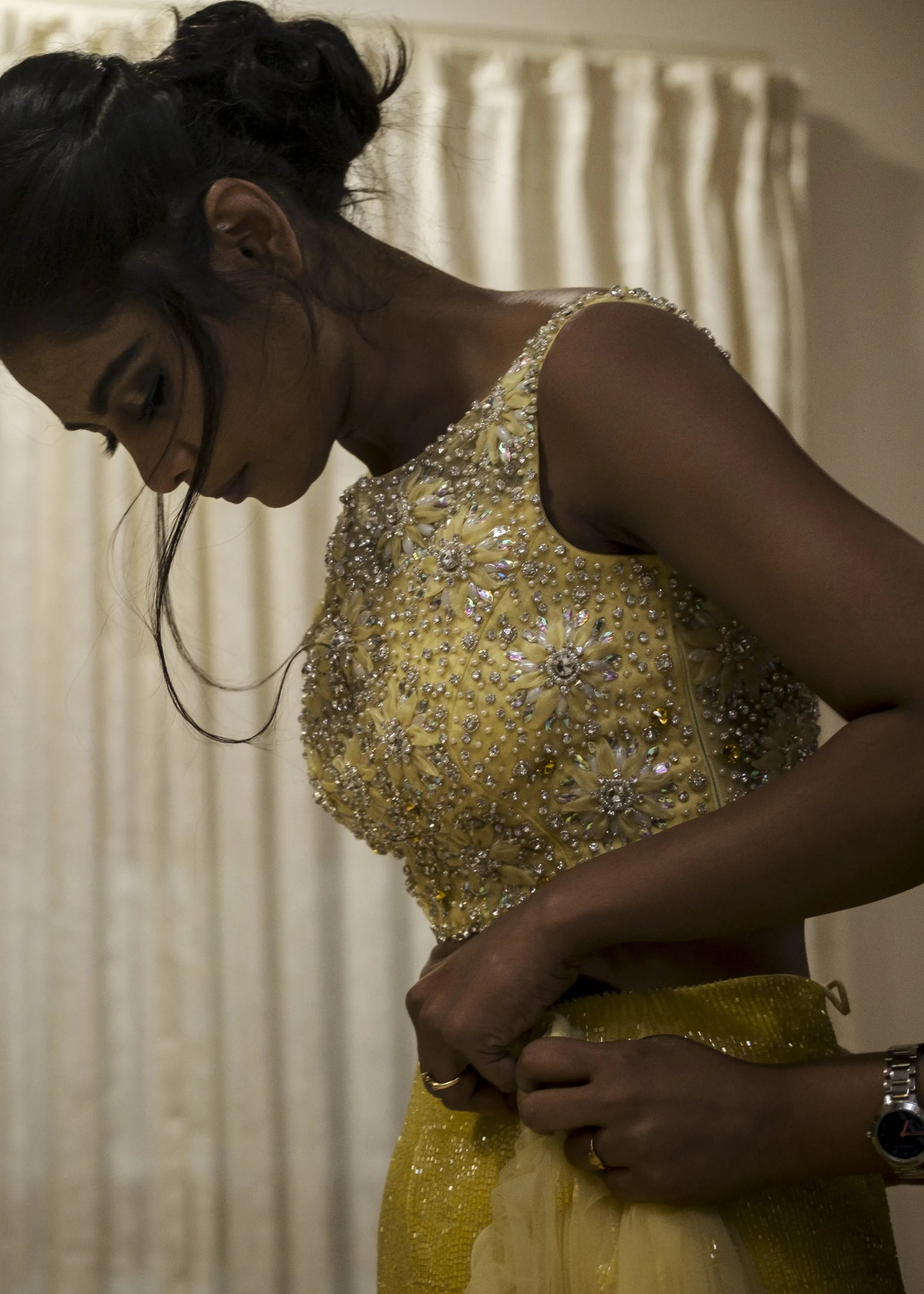 Bride from Chennai during makeup in handcrafted yellow mermaid lehenga embellished with cut dana, pearls, rhinestones and handmade 3D flowers.