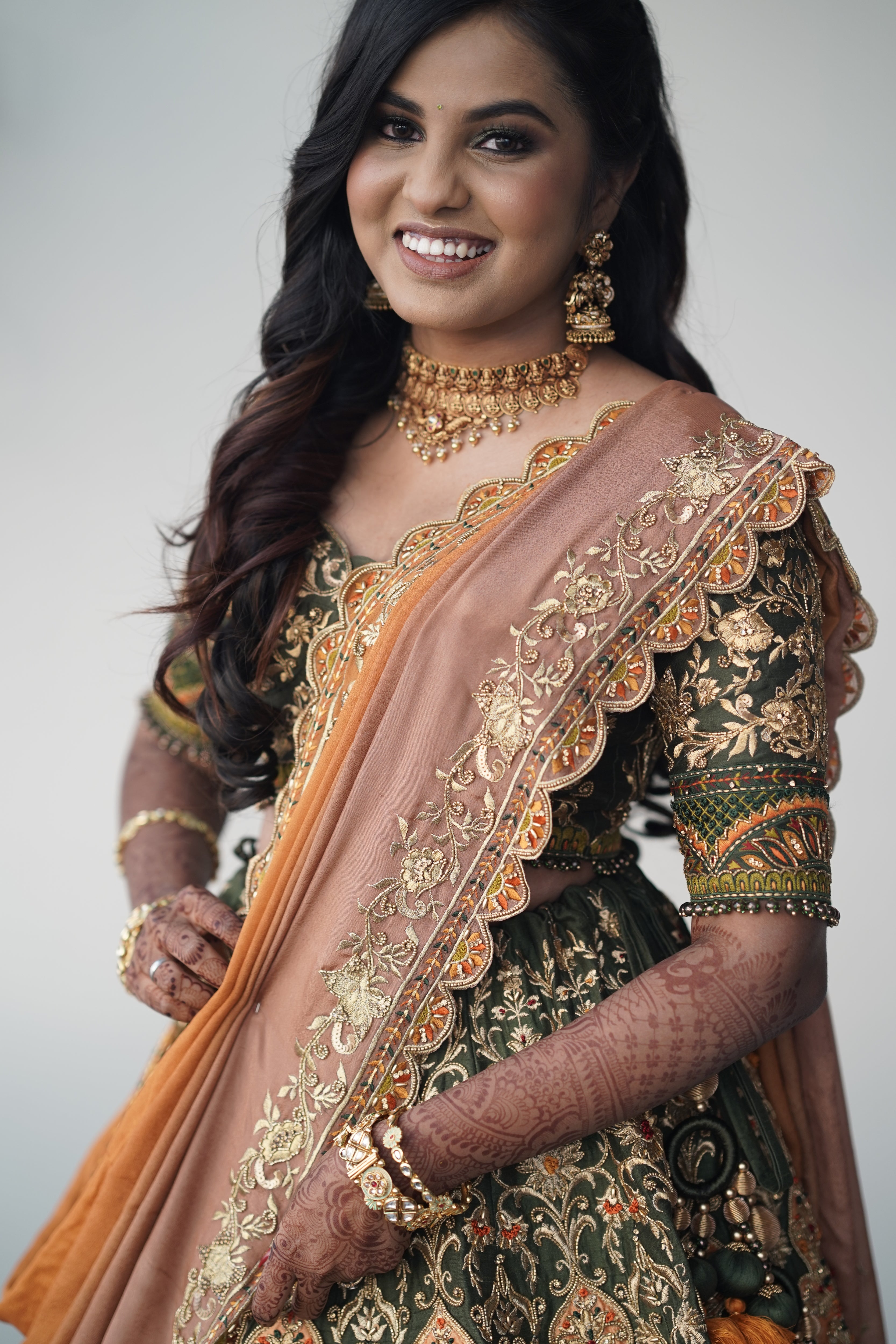 Bride from Chennai for a closeup pic in an olive green raw silk lehenga with hints of burnt orange handcrafted intricately with zardozi, crystal beads, resham knot work, cutdanas and sequins. Designed by Archana Karthick.