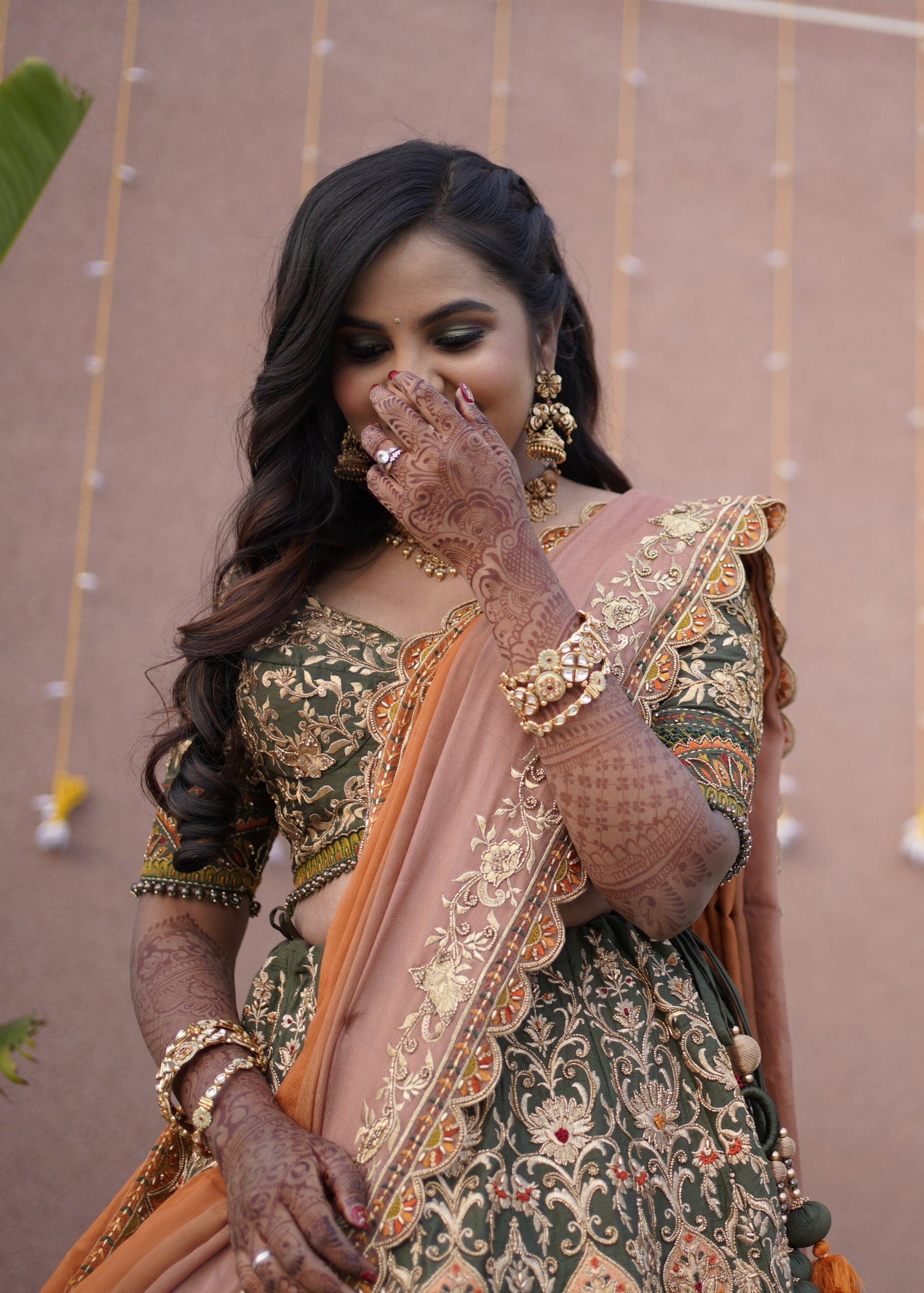 Bride from Chennai for a front shot in an olive green raw silk lehenga with hints of burnt orange handcrafted intricately with zardozi, crystal beads, resham knot work, cutdanas and sequins. Designed by Archana Karthick.