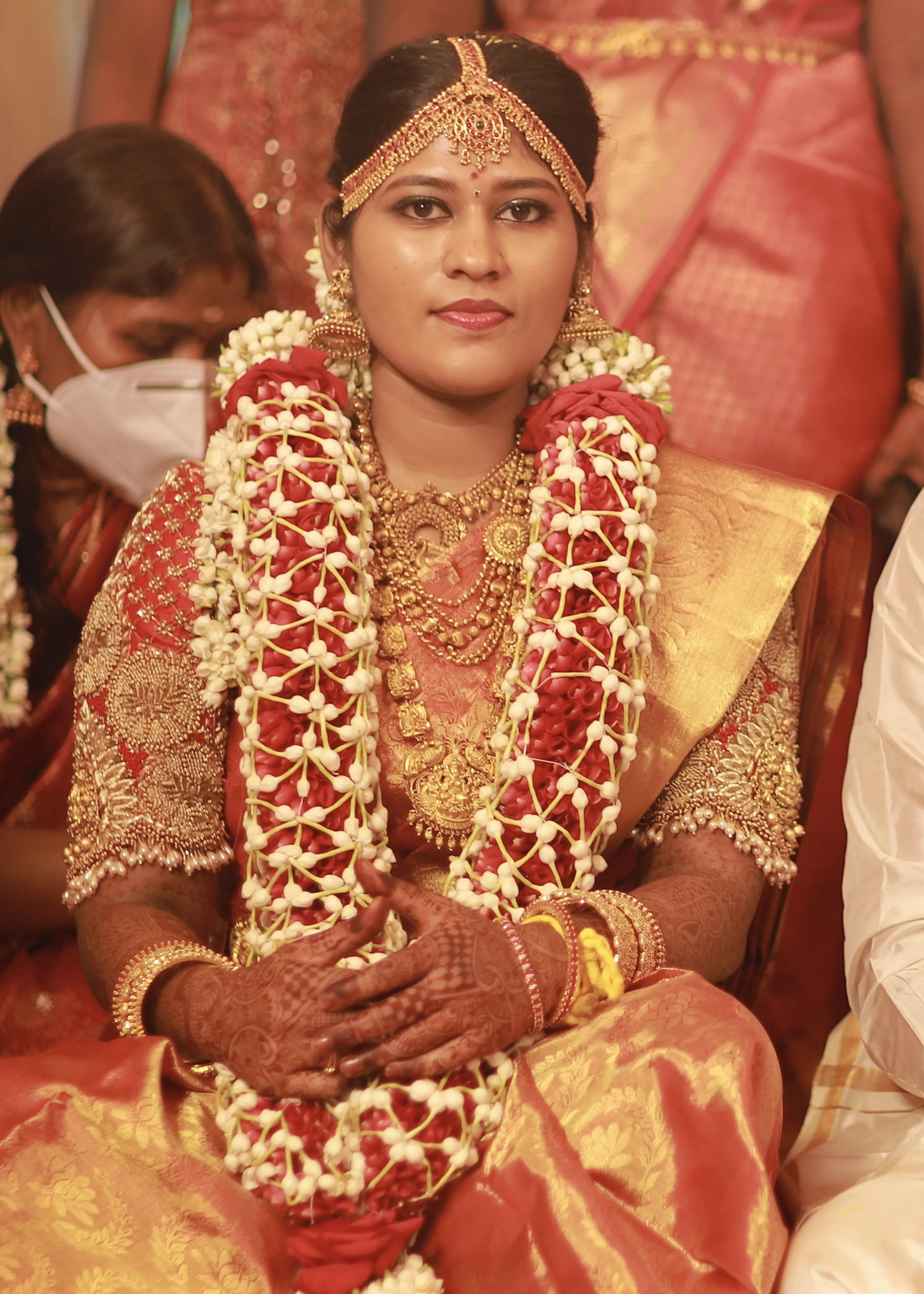 Bride from Chennai in a handcrafted red raw silk blouse embellished with zardozi, pearls, beads with goddess pendants on sleeves.