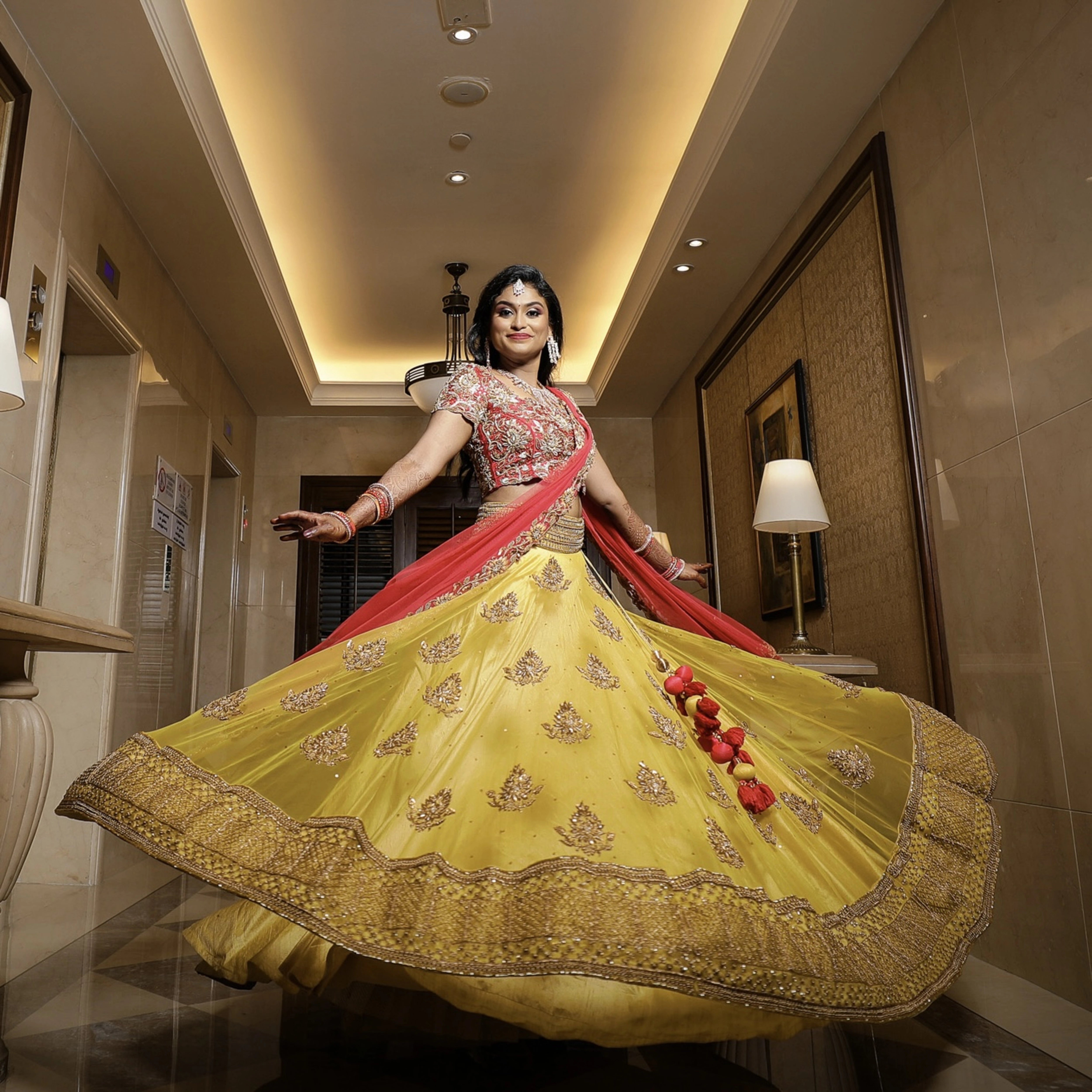Bride from Chennai in a yellow tulle skirt and dupatta and red raw silk blouse which make up the lehenga handcrafted intricately. Designed by Archana Karthick.