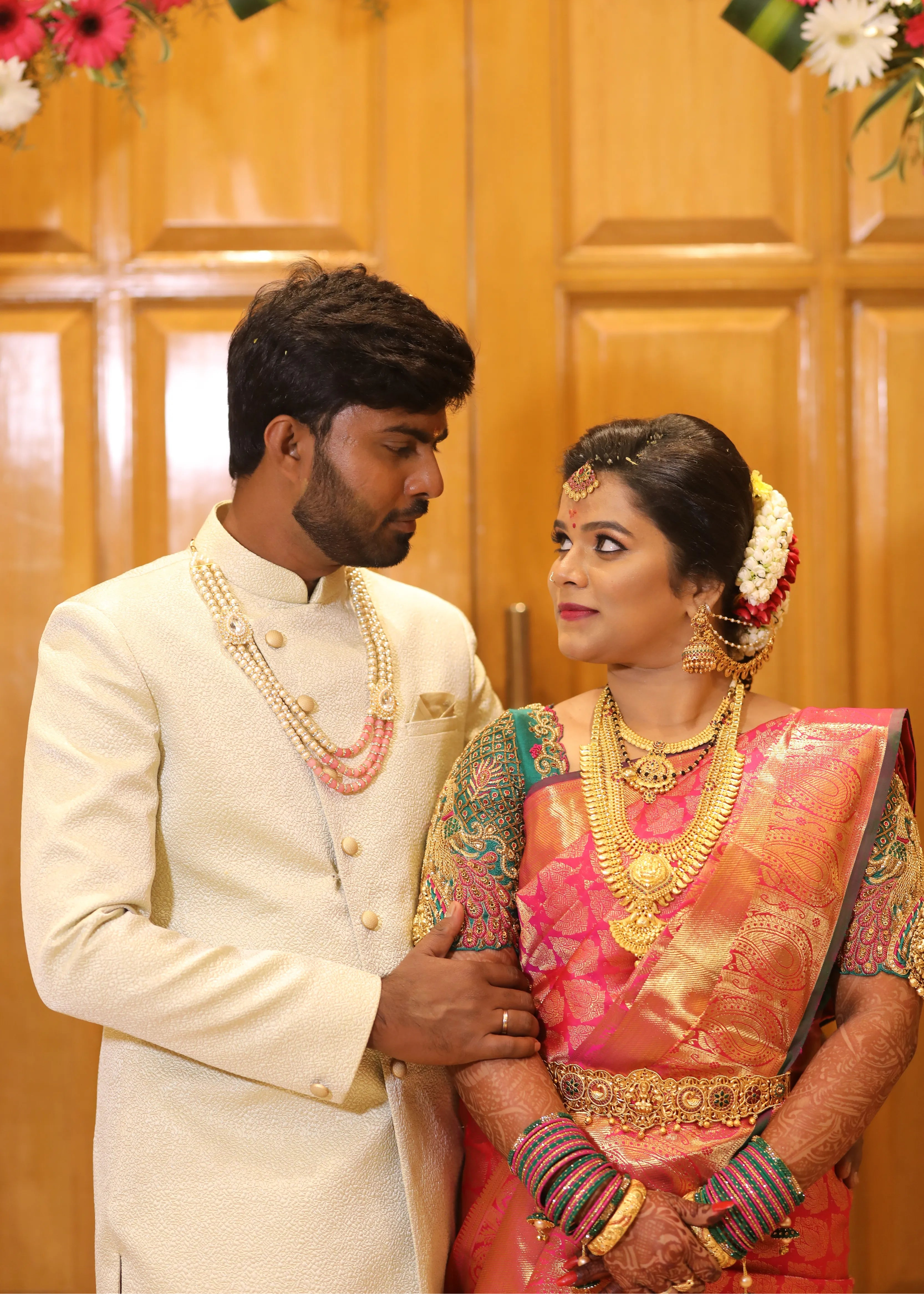 Bride from Chennai looking at groom in a handcrafted peacock concept green silk blouse with goddess pendants on sleeves. Designed by Archana Karthick