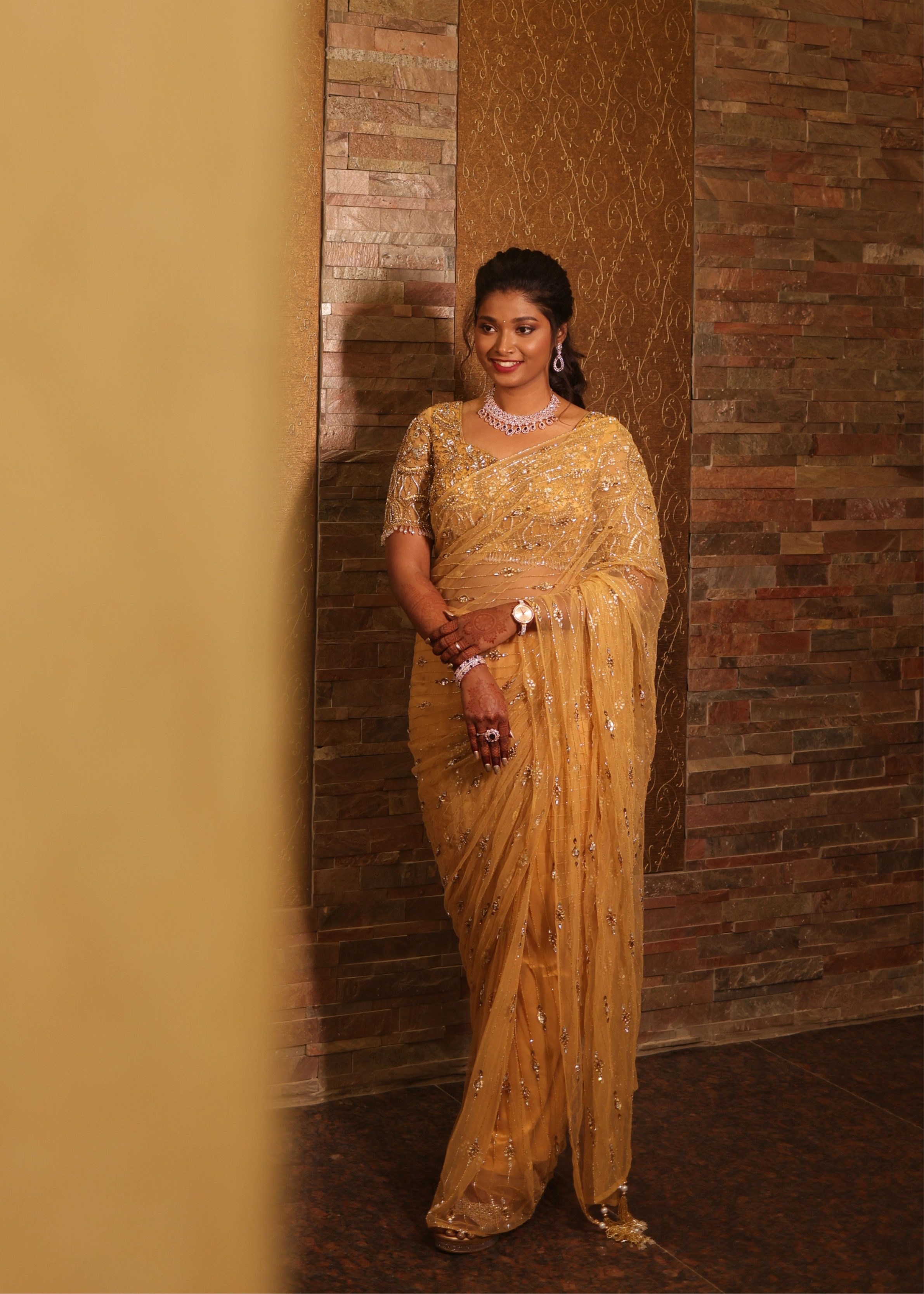 Bride from Chennai looking sideways in a handcrafted metallic gold net saree designed by Archana Karthick with rhinestones