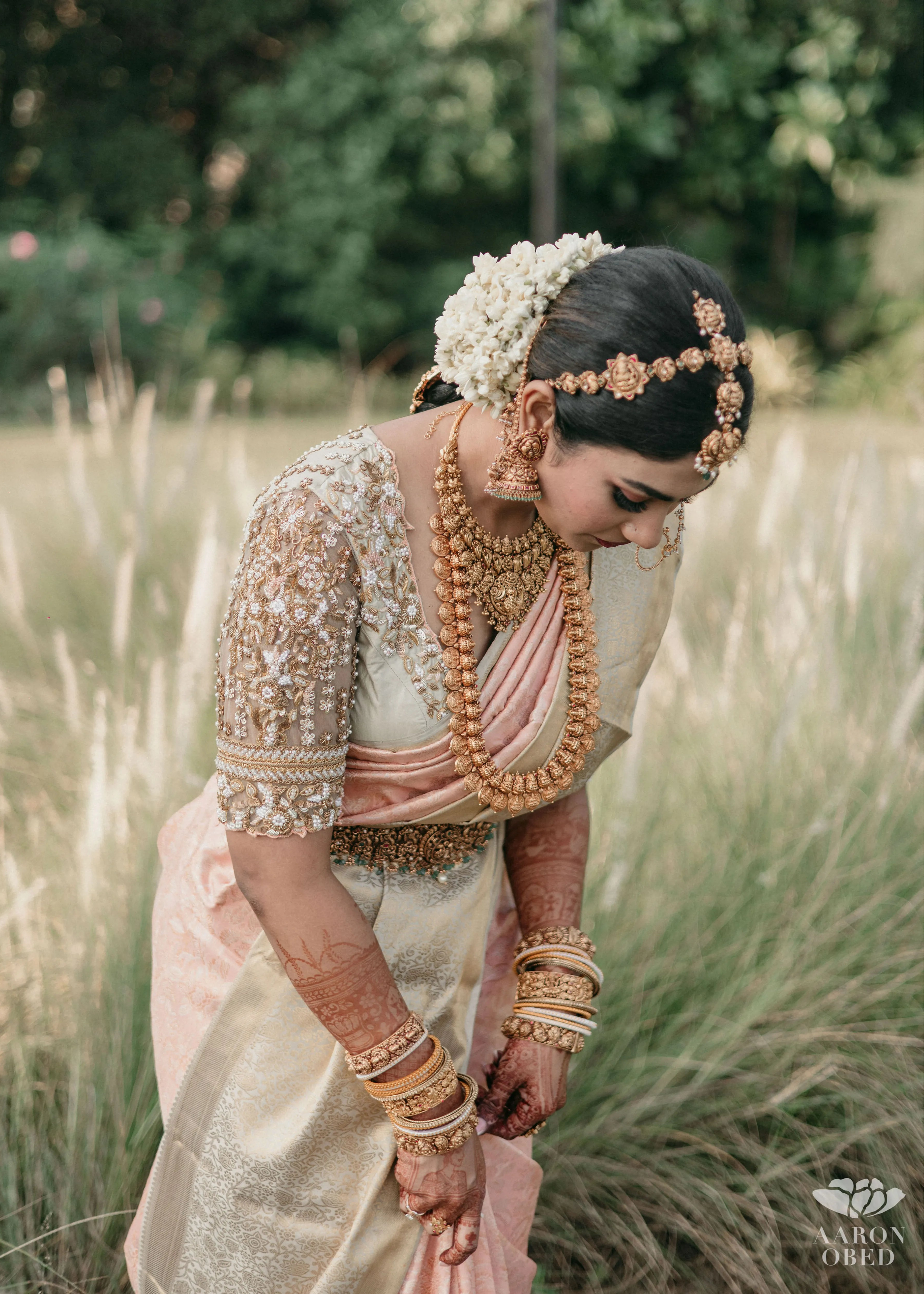 Bride from Chennai pleating her saree in a concept blouse in grey tulle and silk, handcrafted intricately with zardozi, crystal beads, stones, pearls and beads. Designed by Archana Karthick.