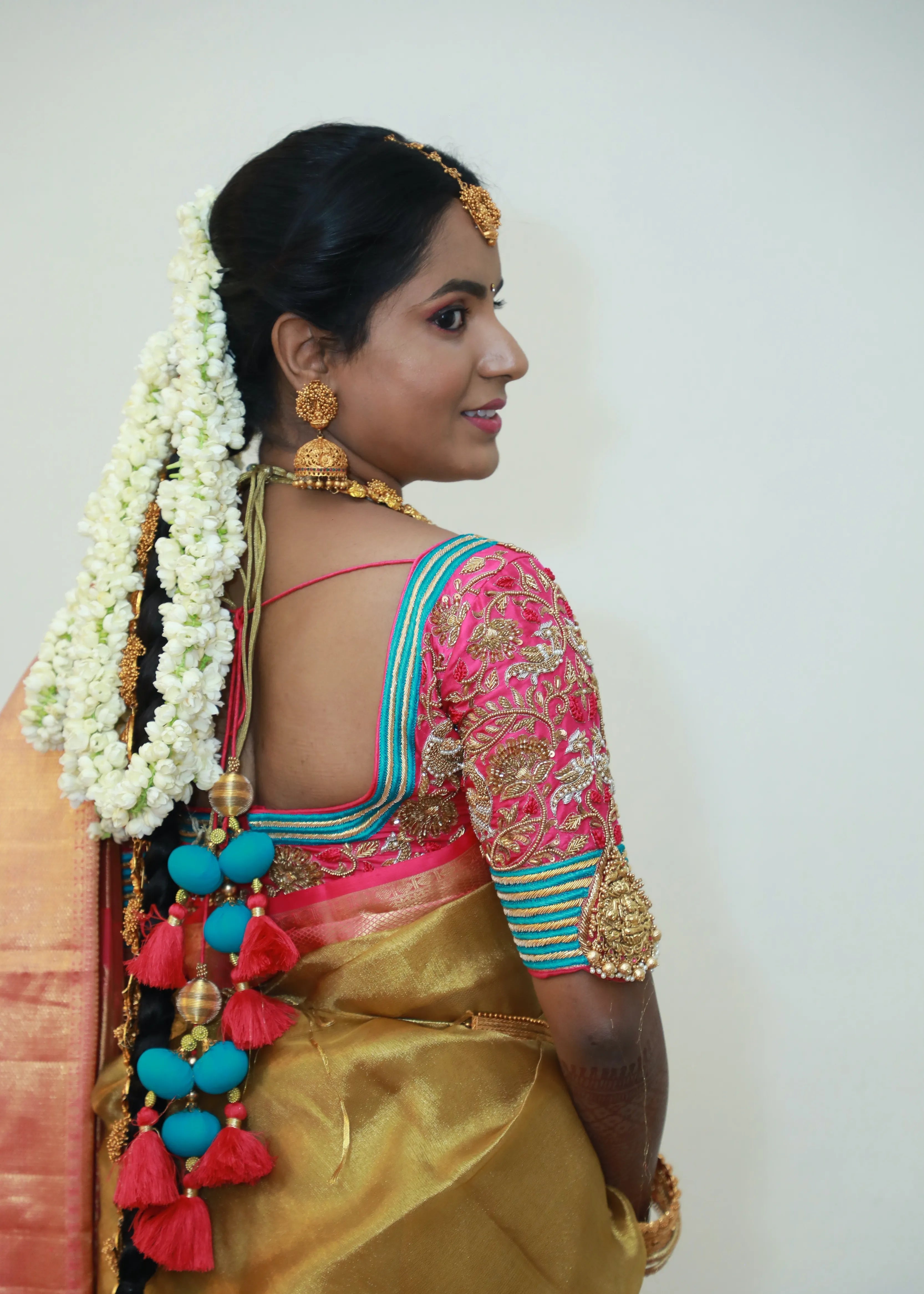 Bride from Chennai posing for back design in pink silk blouse with zardozi, kundan, resham knot work and kundan embellishments. Designed by Archana Karthick