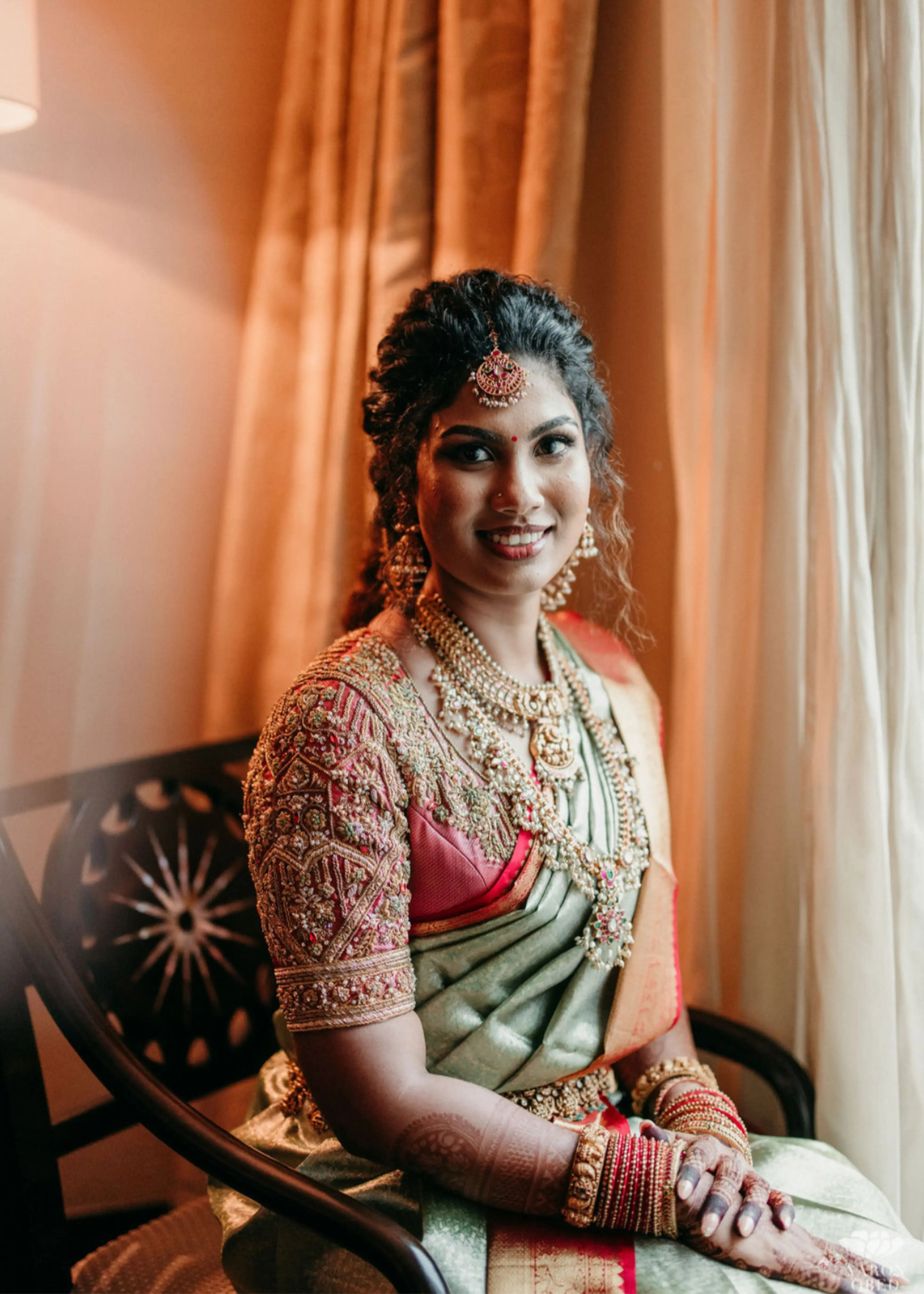 Bride from Chennai posing in a concept red silk blouse handcrafted intricately with rhinestones, pearls, zardozi, resham knot work and stones. Designed by Archana Karthick