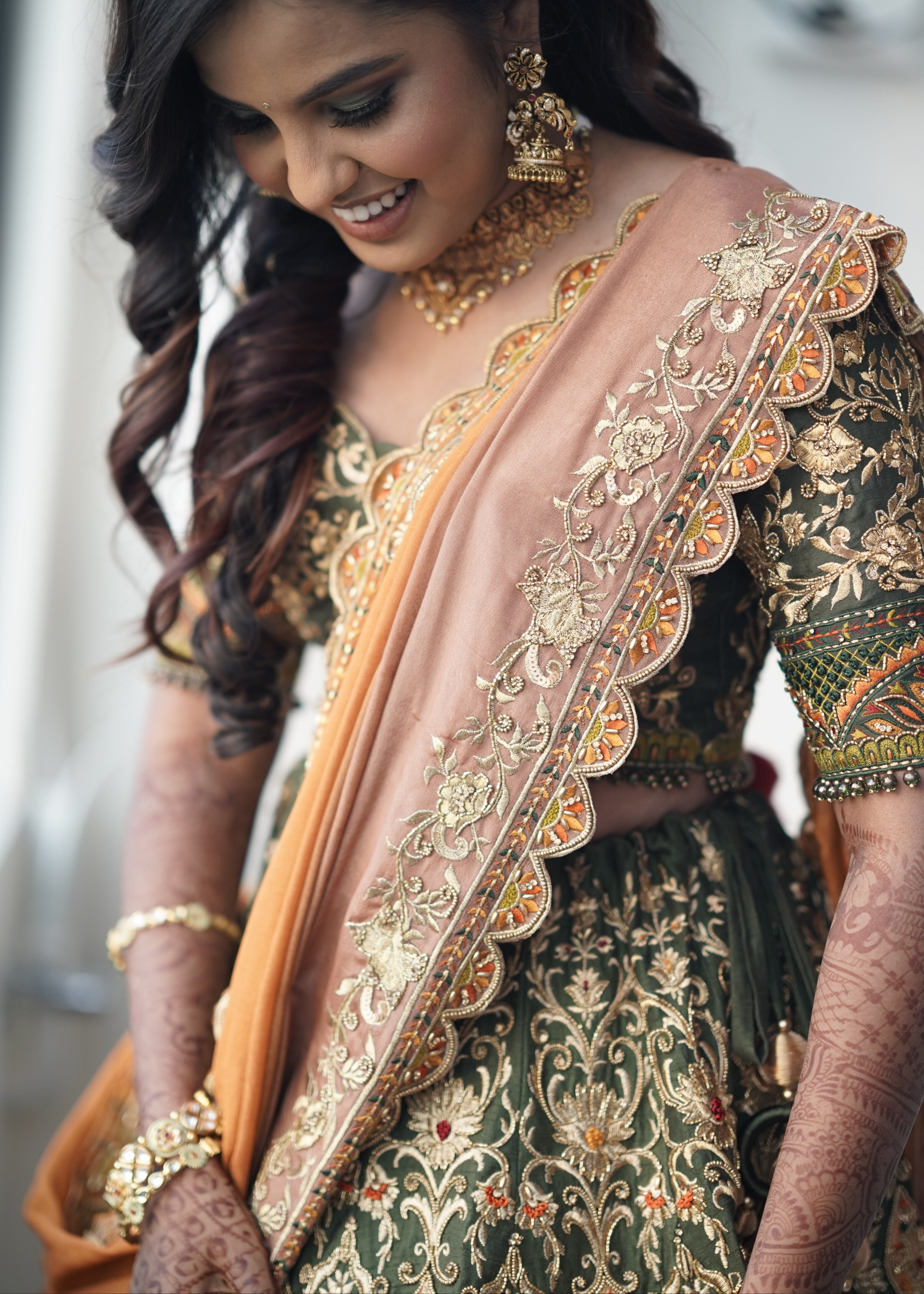 Bride from Chennai posing in an olive green raw silk lehenga with hints of burnt orange handcrafted intricately with zardozi, crystal beads, resham knot work, cutdanas and sequins. Designed by Archana Karthick.