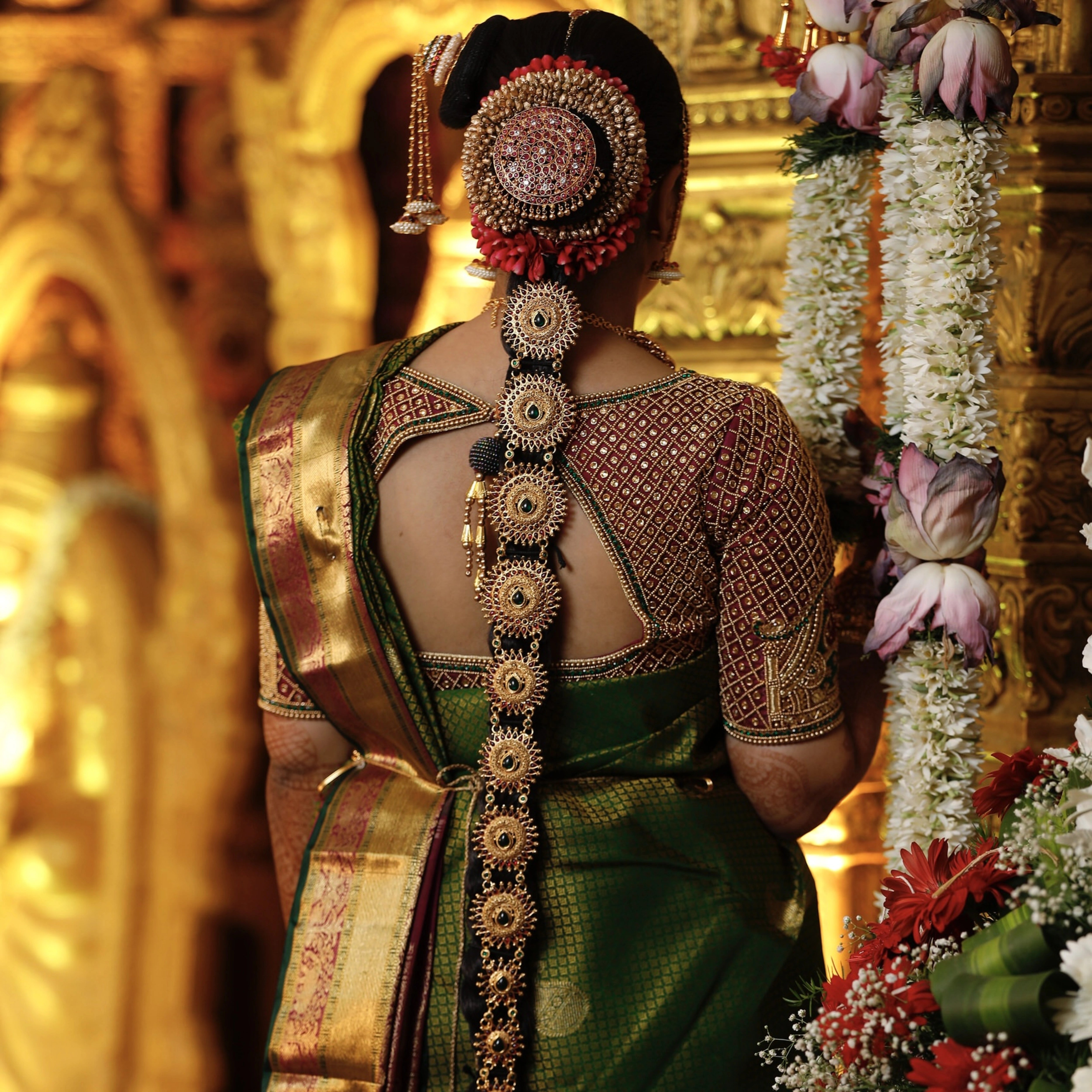Bride from Chennai posing on stage for back design in a silk blouse designed by Archana Karthick handcrafted intricately with zardozi, beads, resham and kundan.