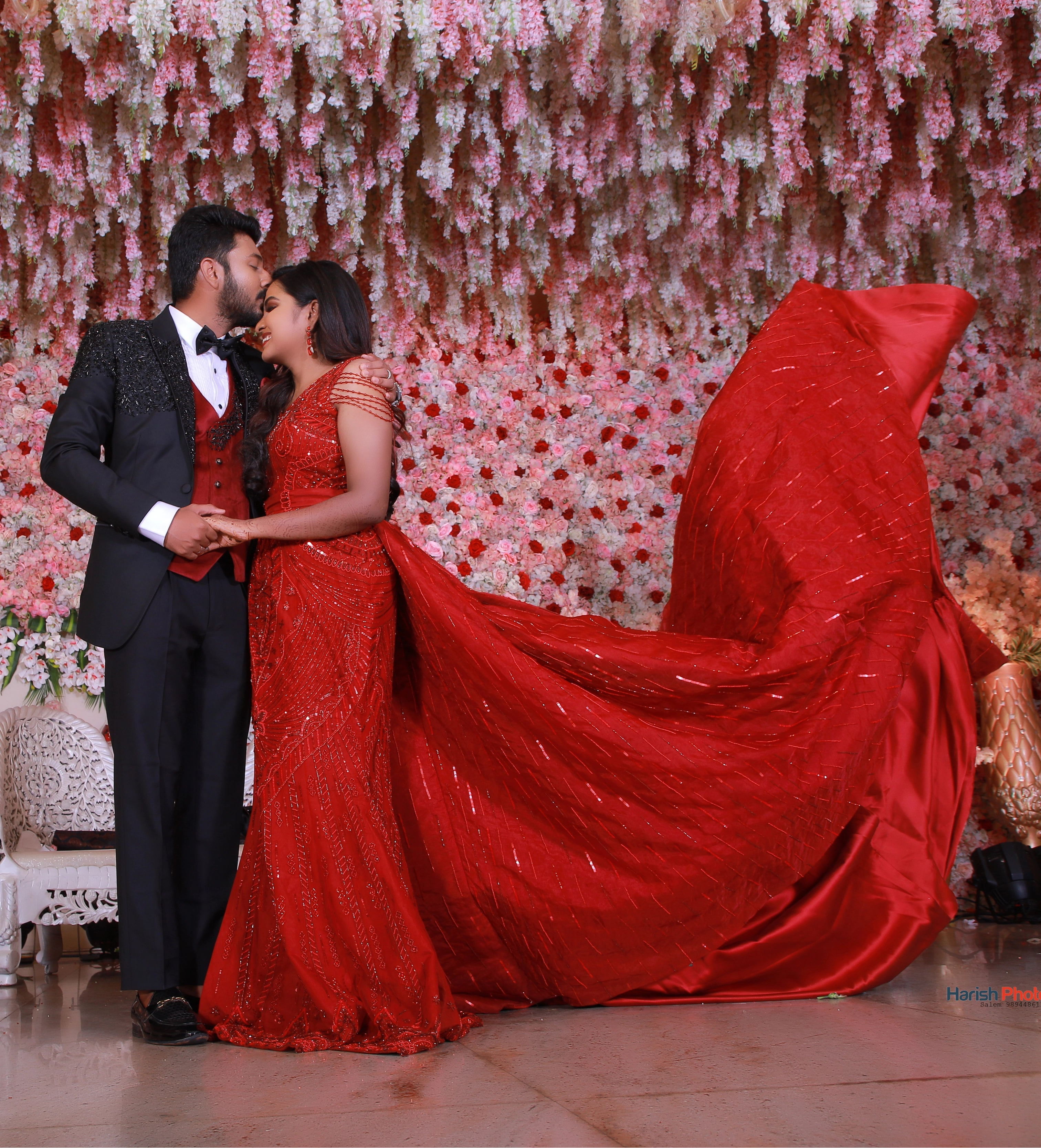 Bride from Chennai posing on stage in a red mermaid gown with detachable trail handcrafted with rhinestones, crystal beads, cutdanas and sequins. Designed by Archana Karthick