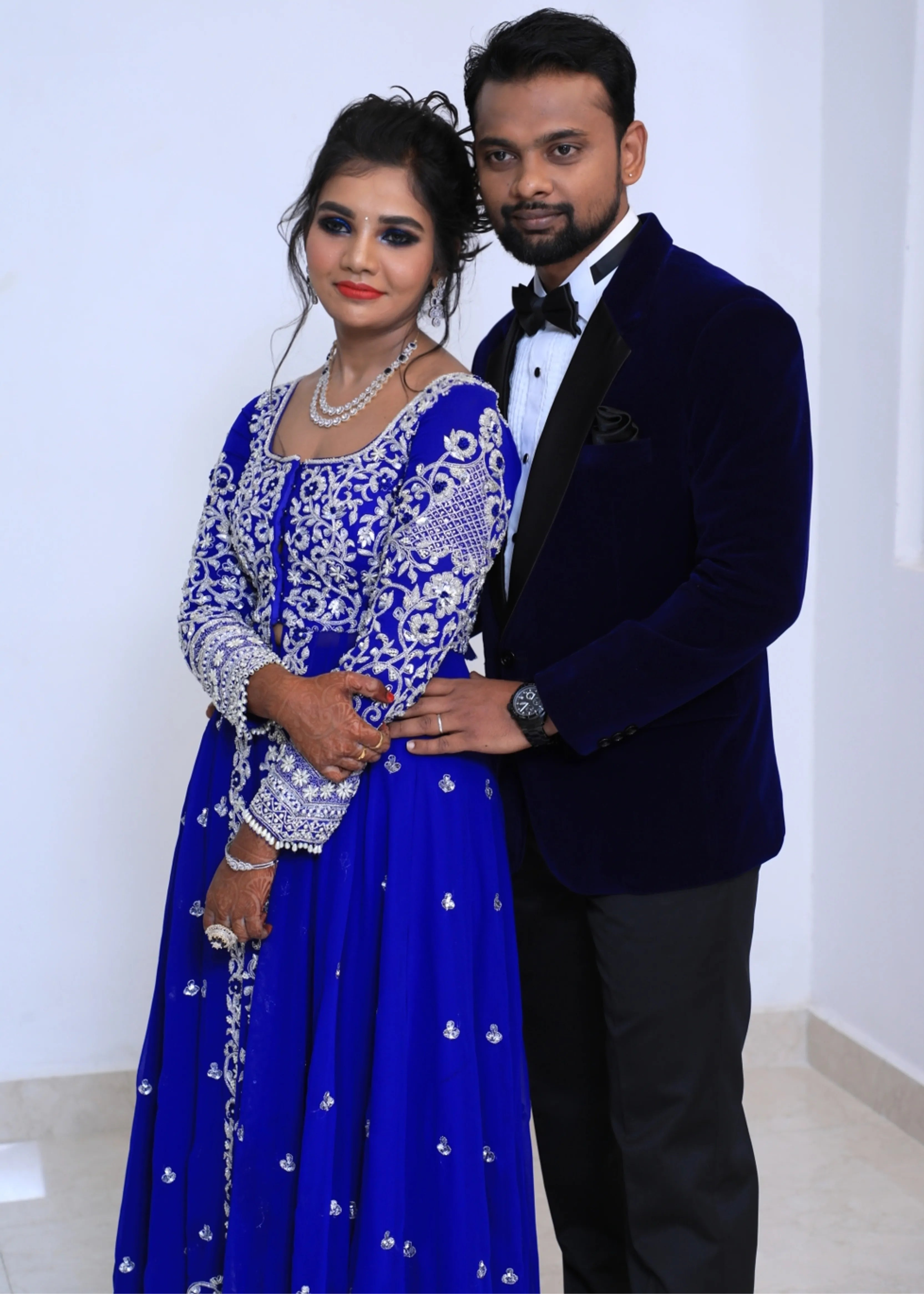 Bride from Chennai posing with groom for a photo in navy blue masakali lehenga with silver embellishments designed by Archana Karthick