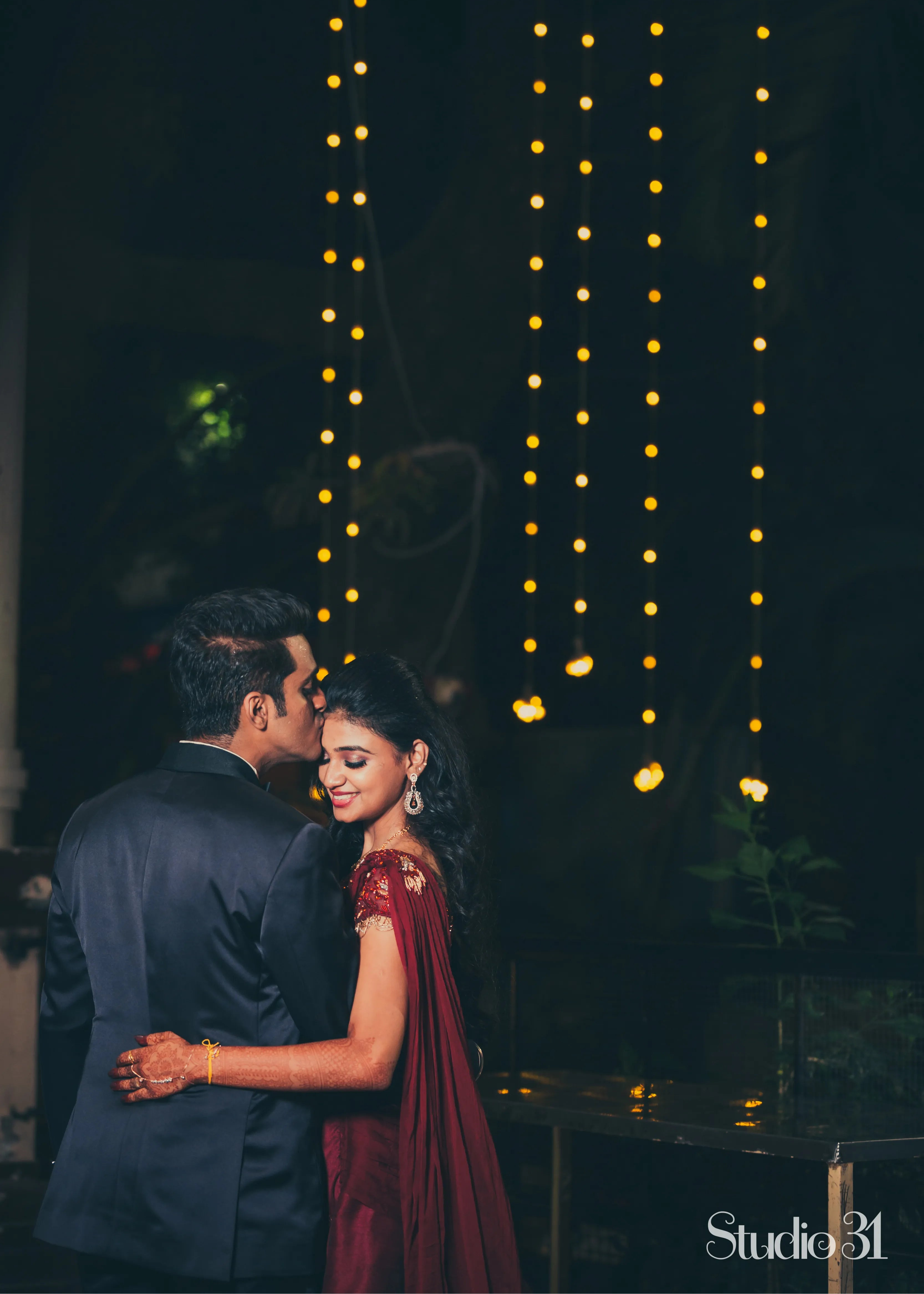 Bride from Chennai posing with groom in a handcrafted maroon raw silk gown with draped dupatta.
