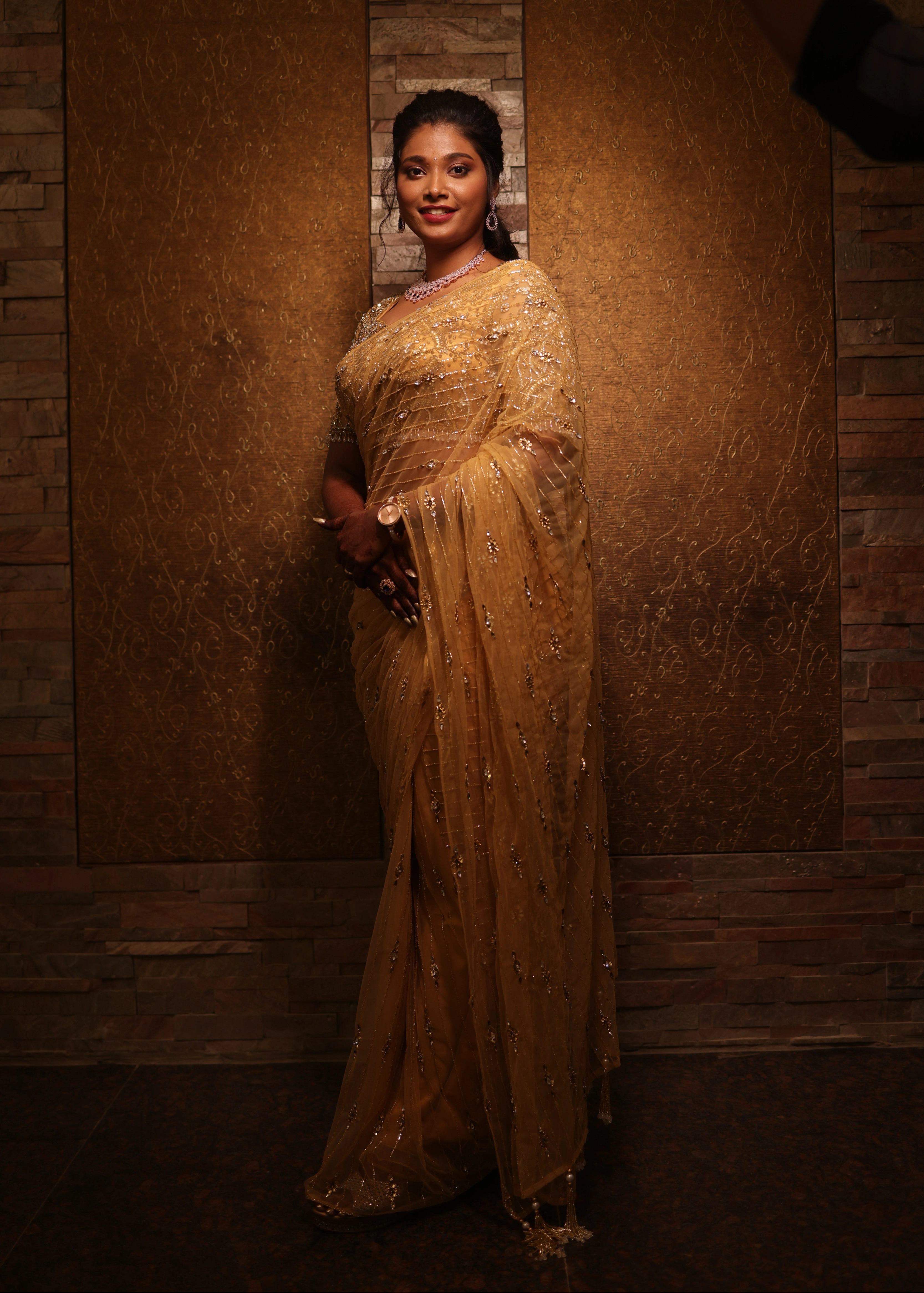 Bride from Chennai smiling at camera in a handcrafted metallic gold net saree designed by Archana Karthick with rhinestones
