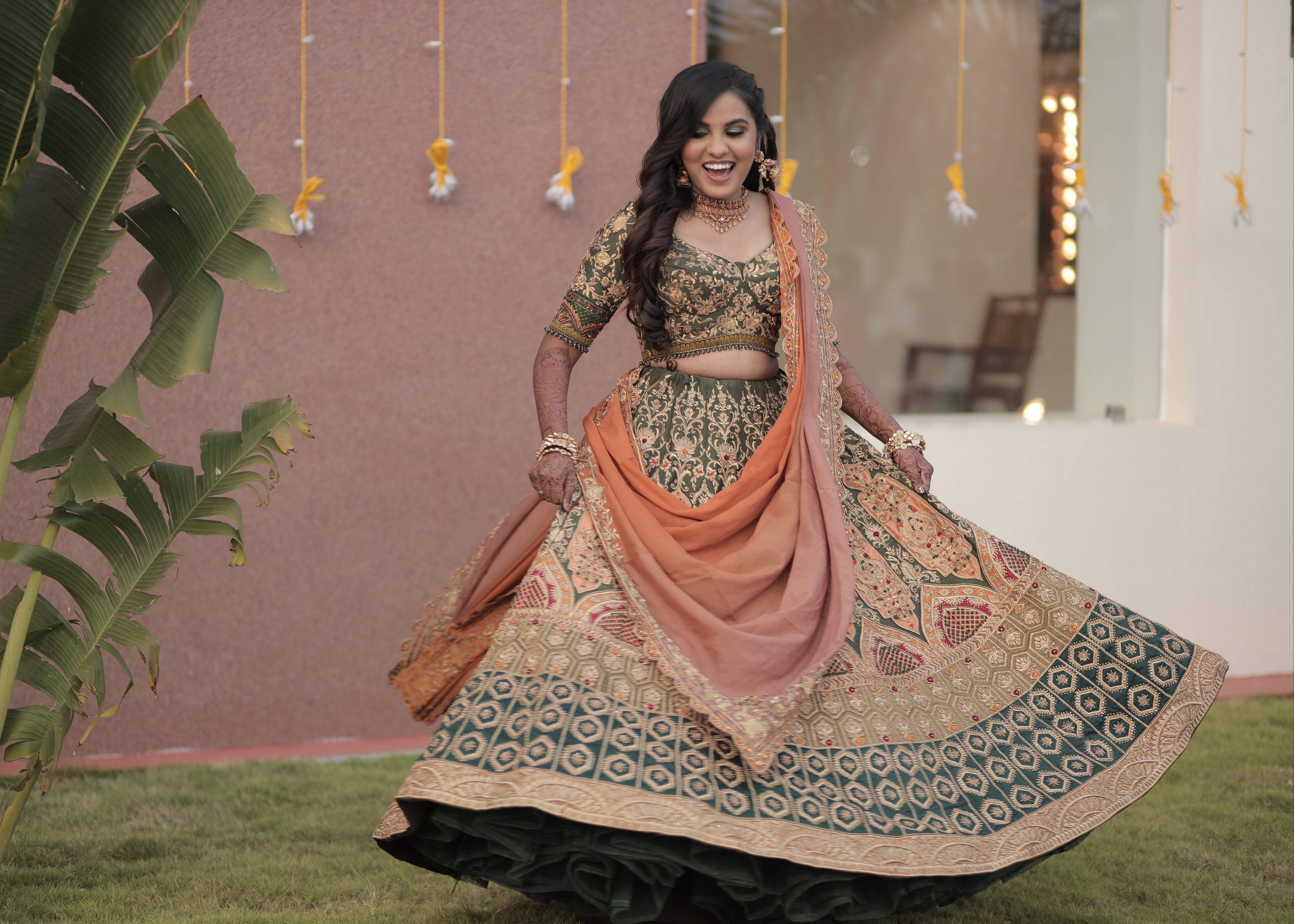 Bride from Chennai twirling in an olive green raw silk lehenga with hints of burnt orange handcrafted intricately with zardozi, crystal beads, resham knot work, cutdanas and sequins. Designed by Archana Karthick.