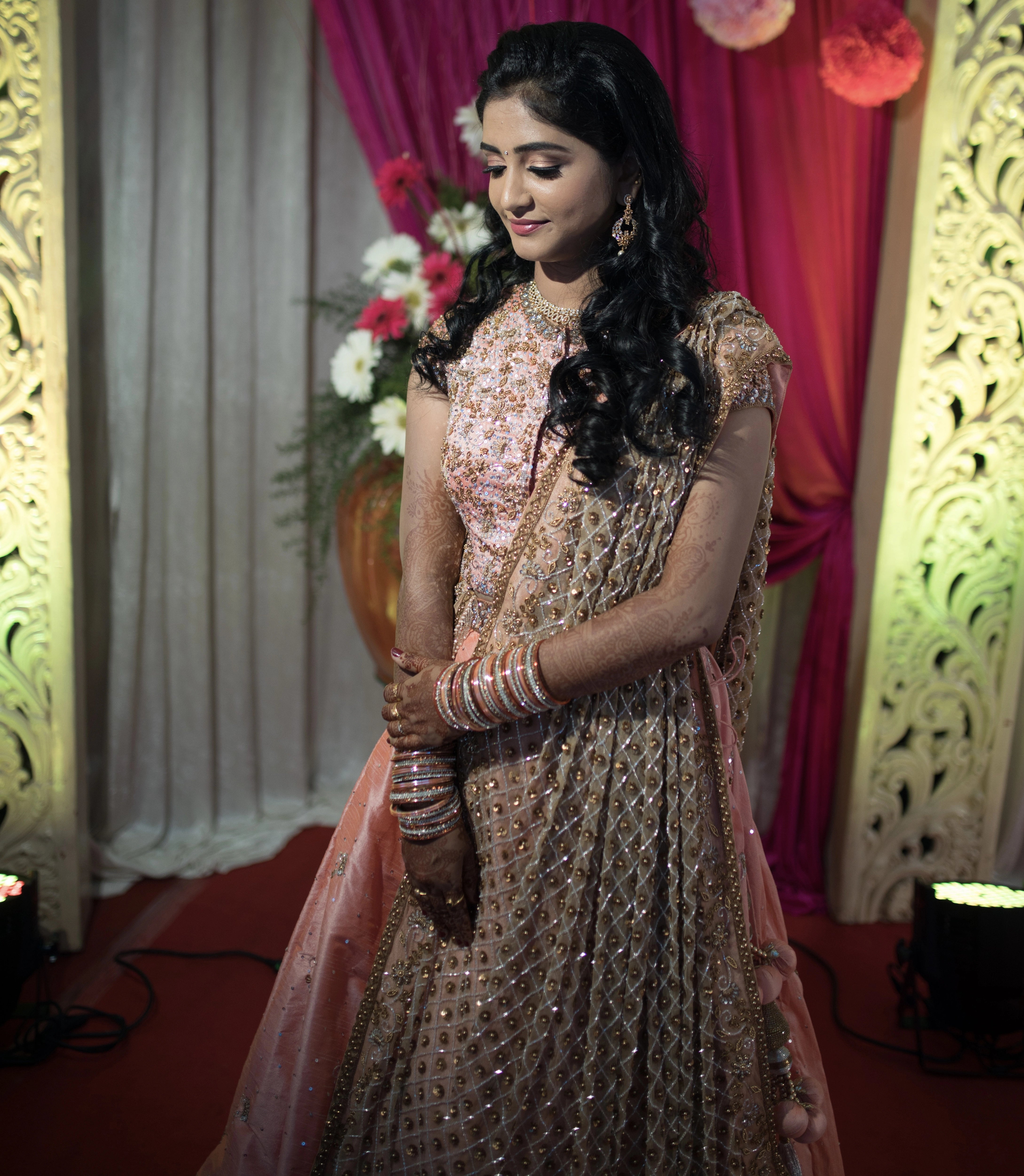 Bride from Coimbatore in a peach raw silk lehenga and tulle dupatta handcrafted intricately with beads, sequins, and cutdana by team Archana Karthick.