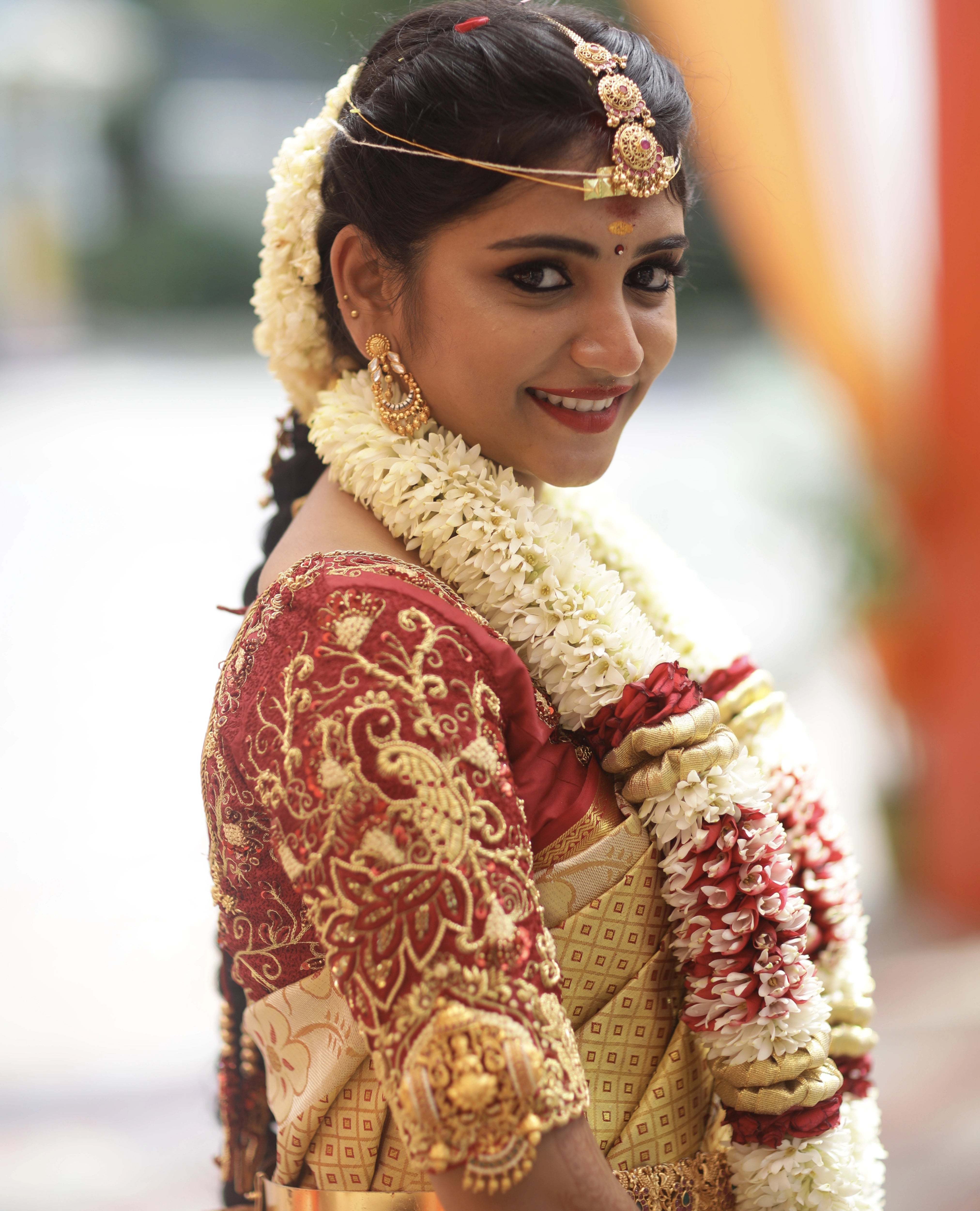 Bride from Coimbatore smiling in a concept maroon silk blouse designed by Archana Karthick handcrafted intricately with zardozi, beads, resham knots and kundan.