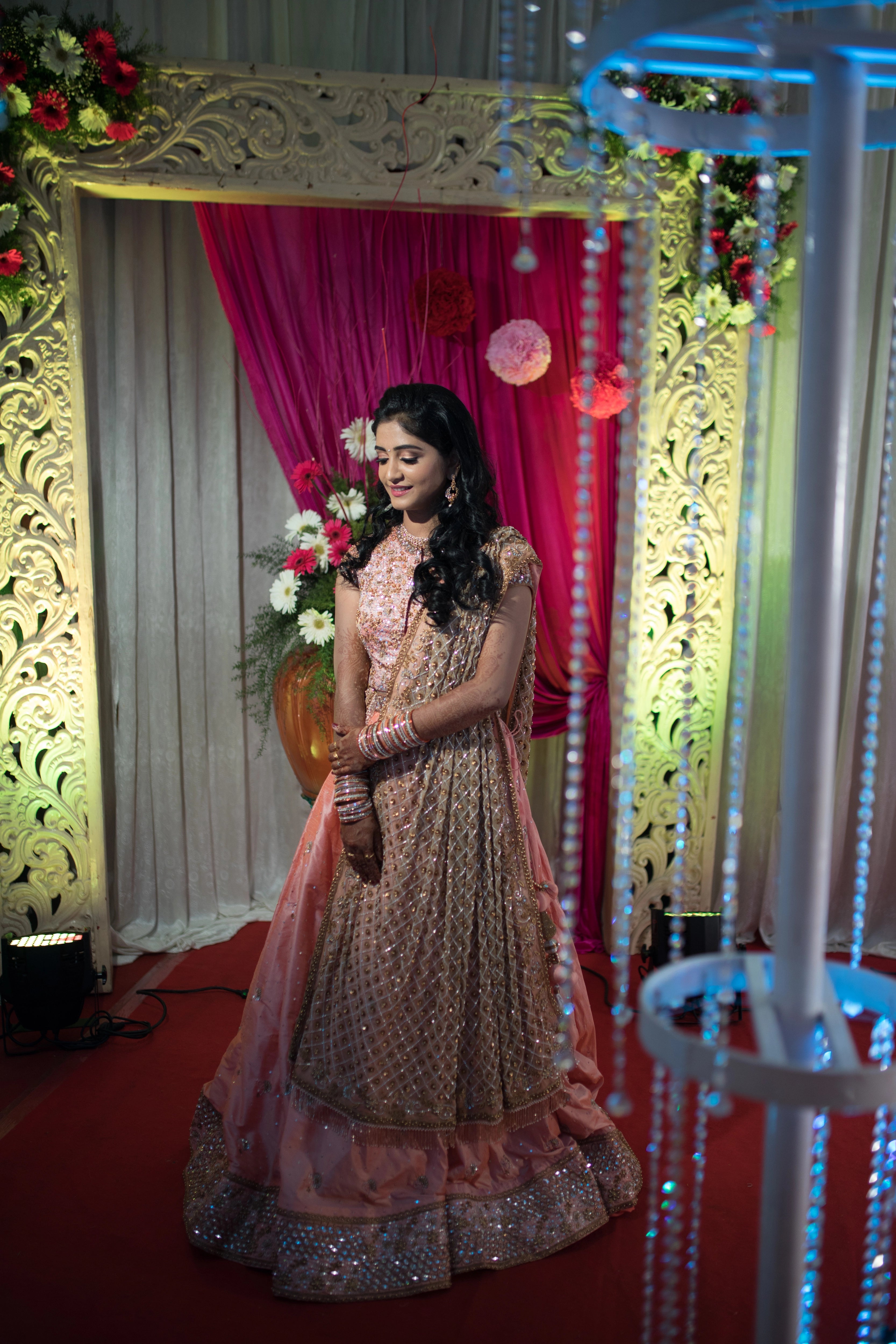 Bride from Coimbatore smiling in a peach raw silk lehenga and tulle dupatta handcrafted intricately with beads, sequins, and cutdana by team Archana Karthick.