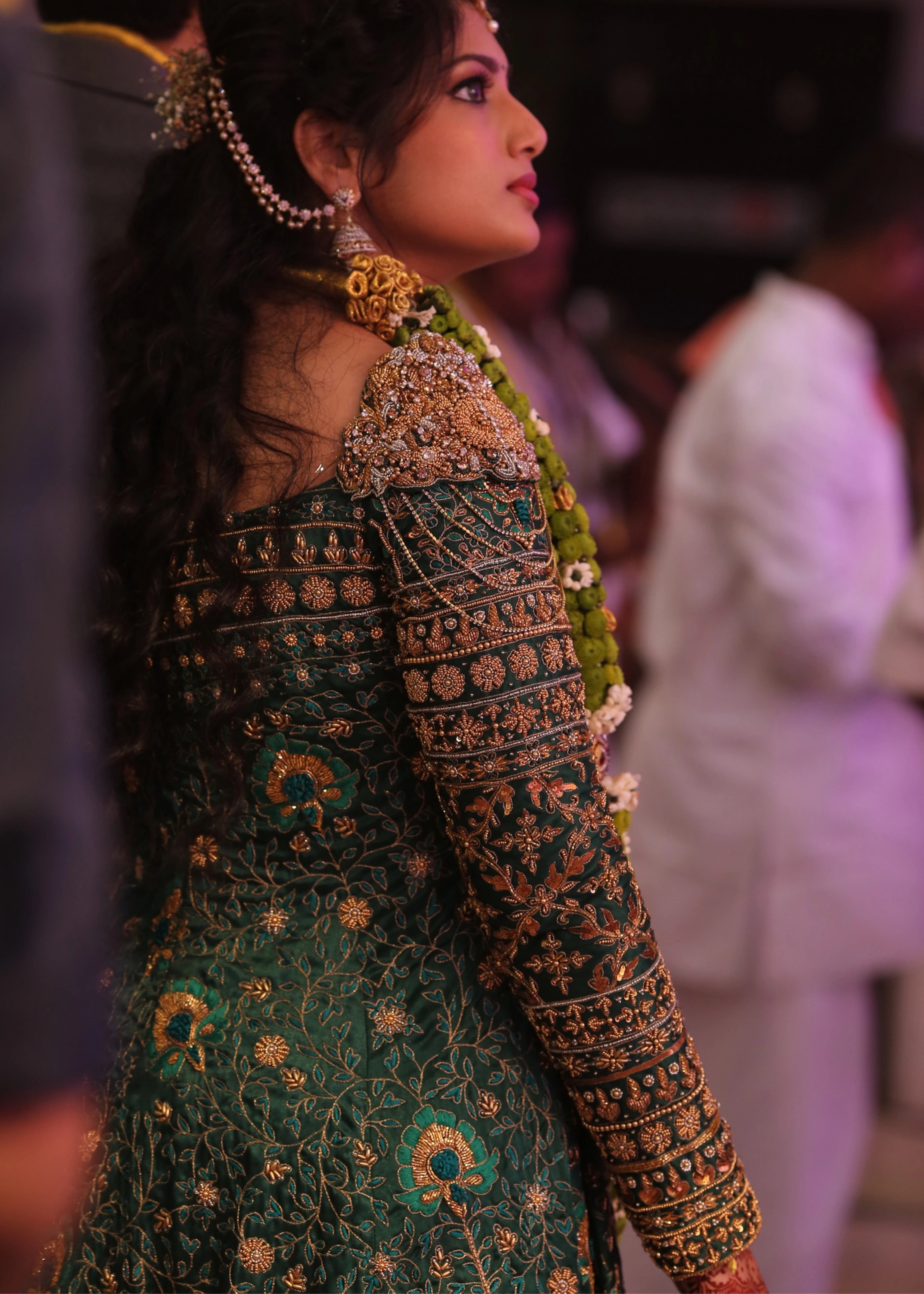 Bride from Kuwait looking away in a bottle green satin silk masakali lehenga handcrafted with zardozi, rhinestones, crystals and more. Designed by Archana Karthick.