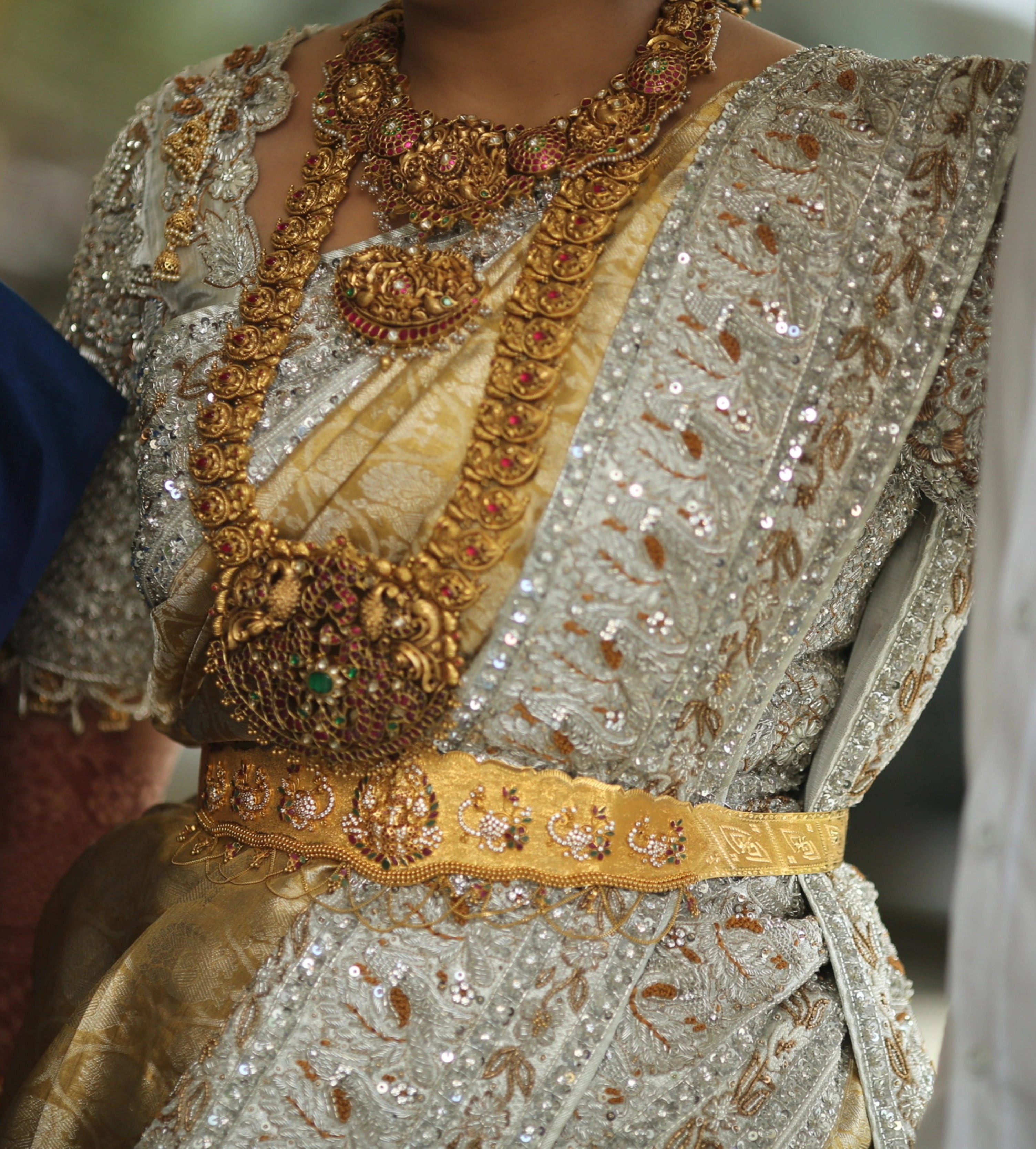 Bride from Kuwait showcasing saree border details in a silver silk blouse and saree border handcrafted with stones, crystals, zardozi, beads, rhinestones, cutdanas and sequins. Designed by Archana Karthick.