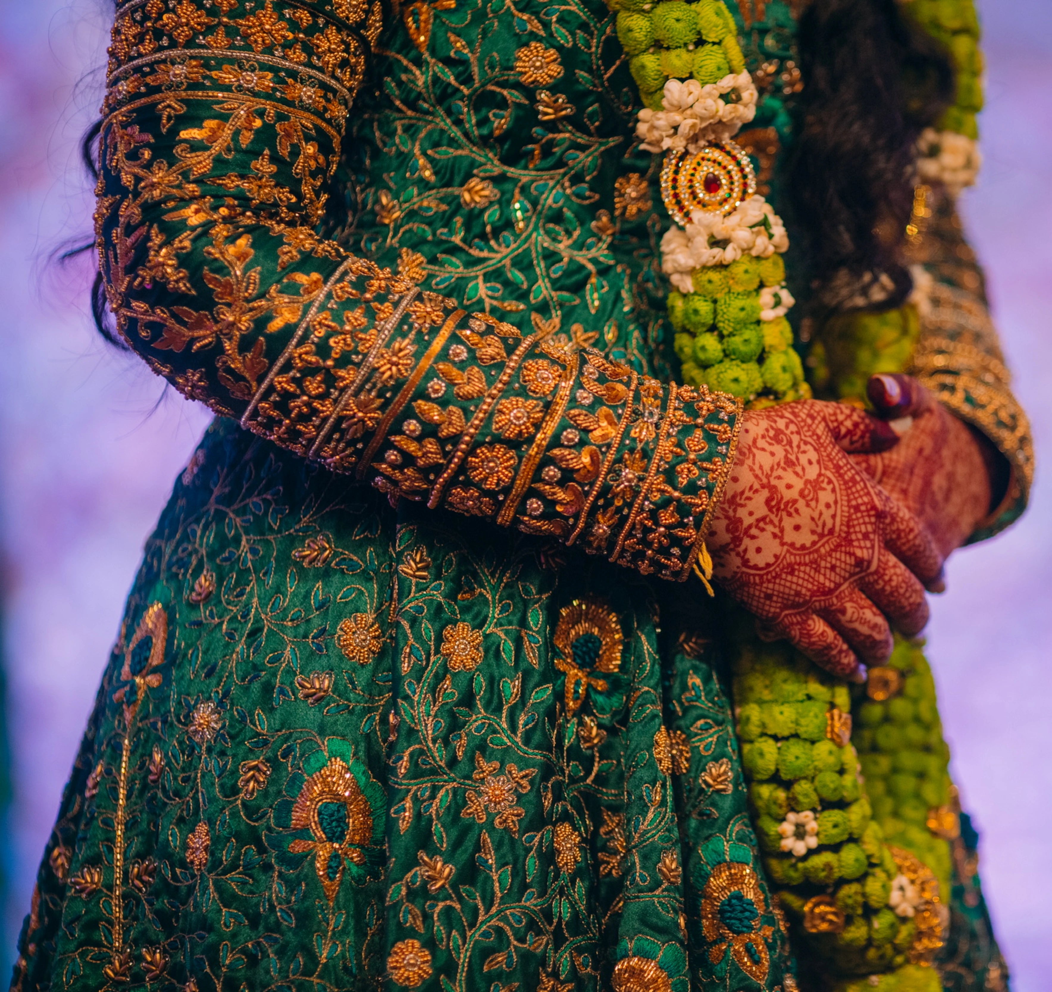 Bride from Kuwait showcasing sleeve intricacy in a bottle green satin silk masakali lehenga handcrafted with zardozi, rhinestones, crystals and more. Designed by Archana Karthick.