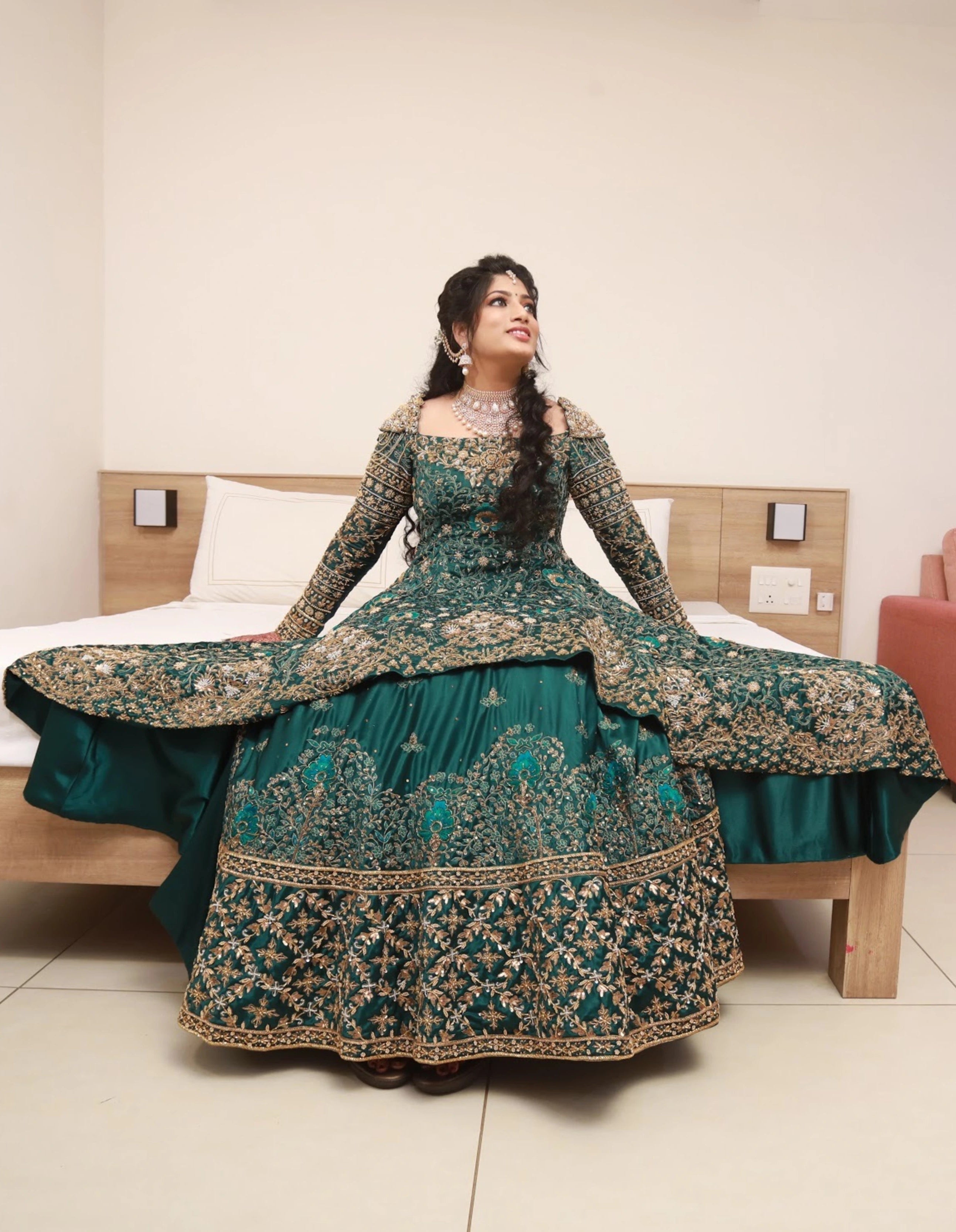 Bride from Kuwait smiling in a bottle green satin silk masakali lehenga handcrafted with zardozi, rhinestones, crystals and more. Designed by Archana Karthick.