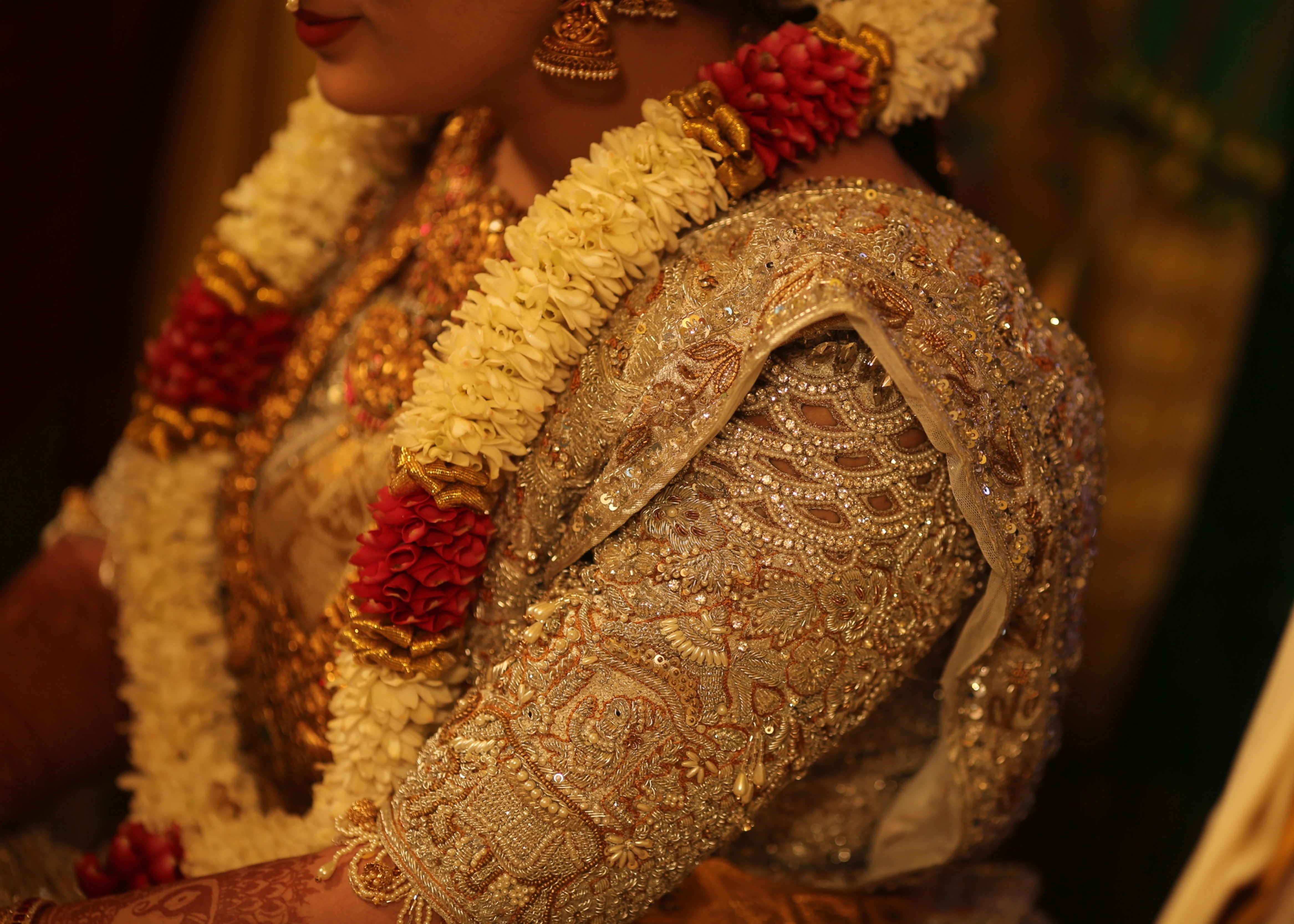 Bride from Kuwait smiling in a silver silk blouse and saree border handcrafted with stones, crystals, zardozi, beads, rhinestones, cutdanas and sequins. Designed by Archana Karthick.