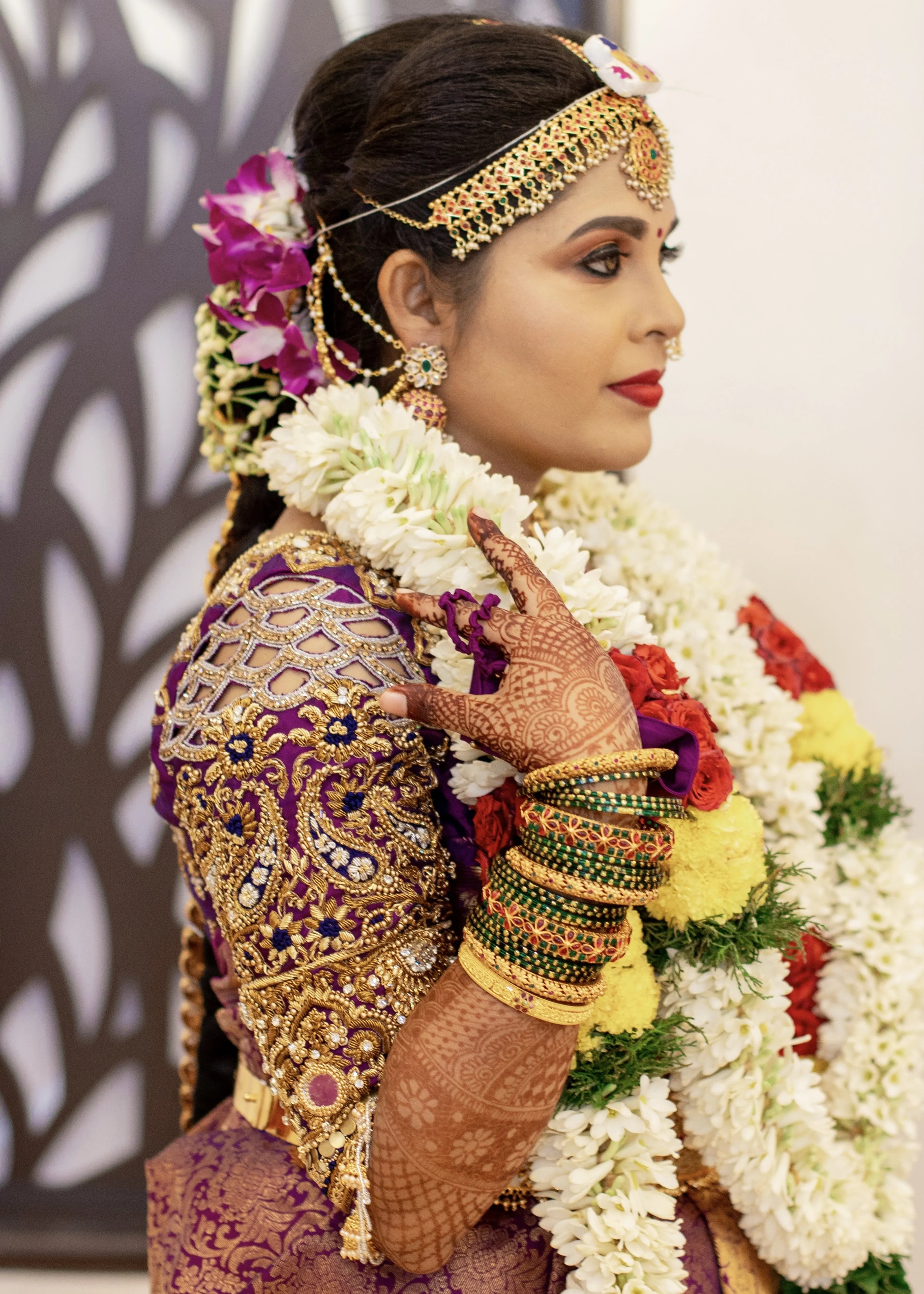 Bride from Salem in a purple silk blouse handcrafted with stone work, zardozi, beads, mirror work resham knot work and jhumki detailings. The cut worked upper arm elvates it.